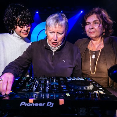 Die 79-jährige Inge Dobrinski (M.) und Ingrid Jatho (r.) lernen von einer DJ-Dozentin neue Fähigkeiten am Mischpult.