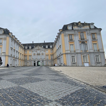 Zu sehen ist eine Gruppe von Menschen, die auf das Schloss zugehen.