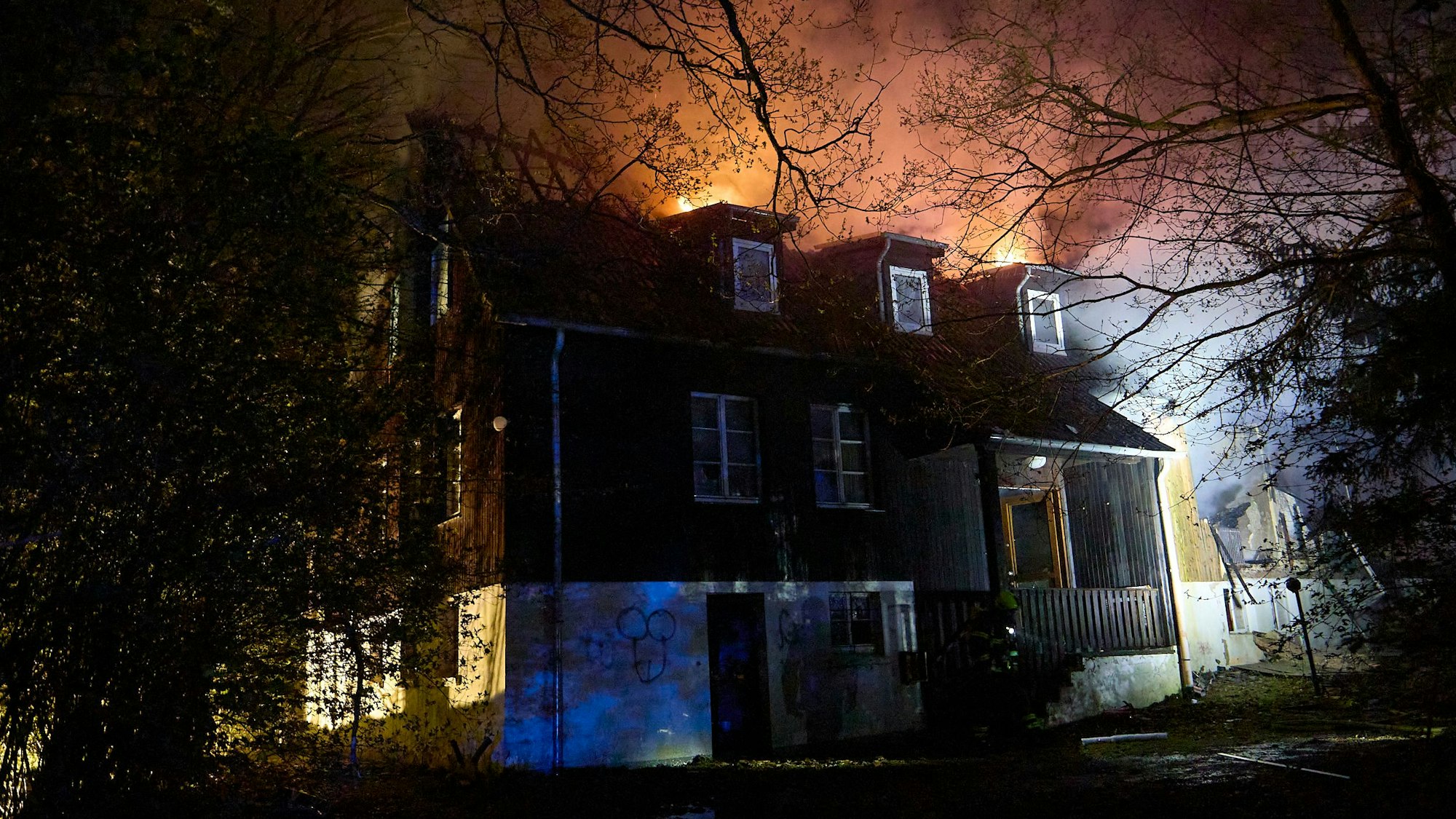 Aus dem Dachstuhl des abseits gelegenen Gebäudes schlagen in der Dunkelheit die Flammen.