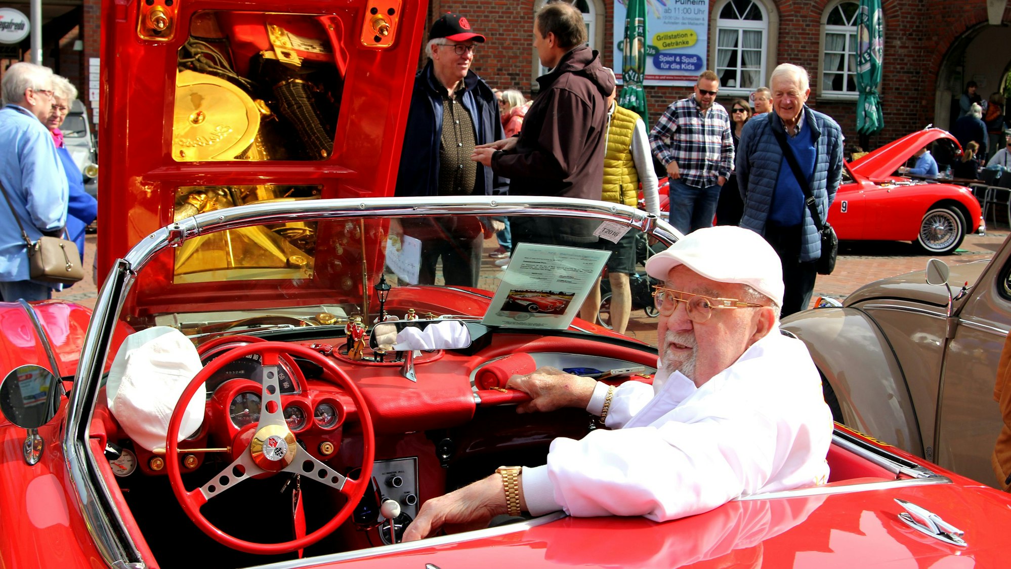 Das Foto zeigt einen Mann in einem roten Oldtimer.