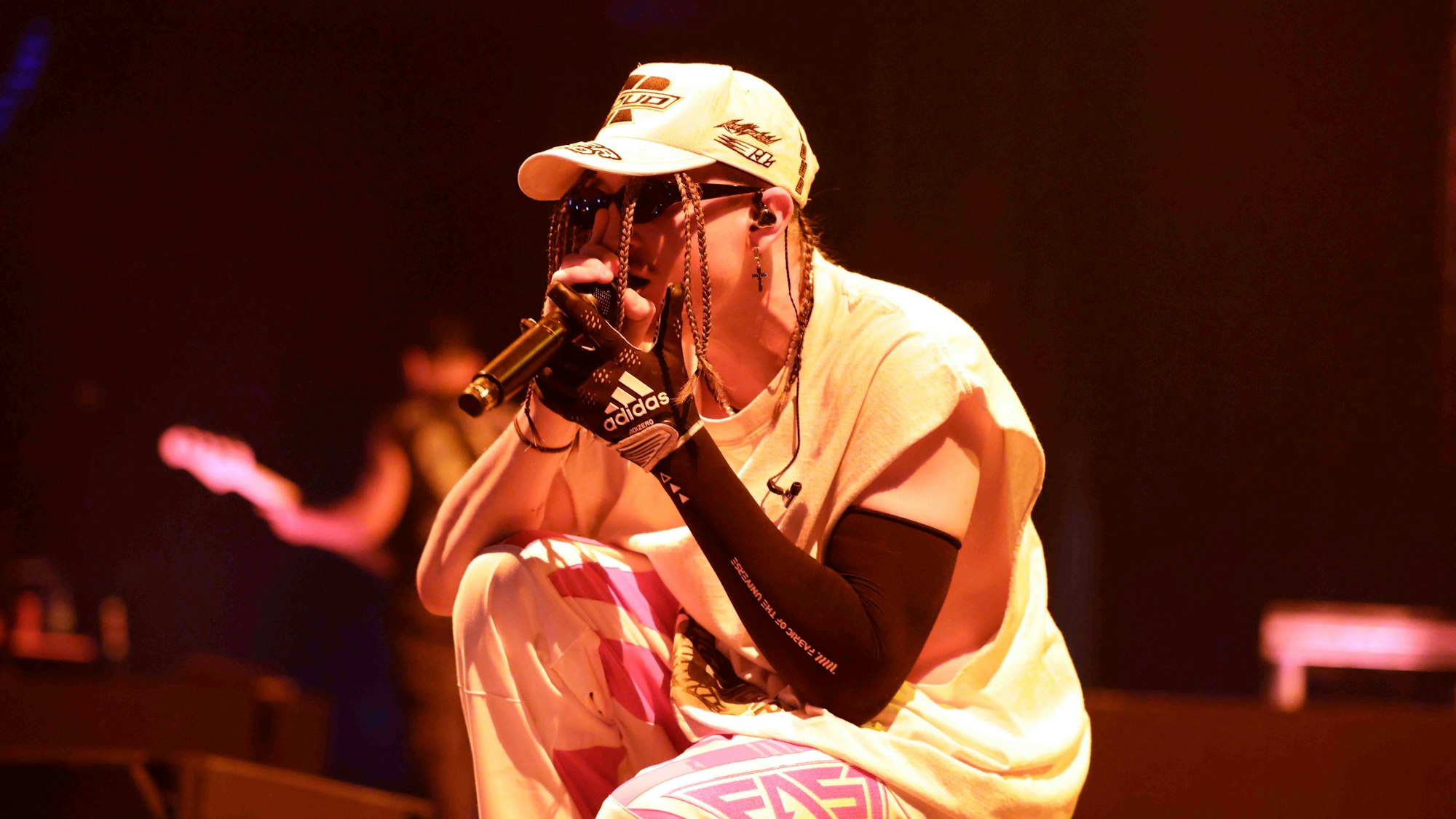 Sänger Mitchel Cave mit Mikrofon, Sonnenbrille und Kappe.