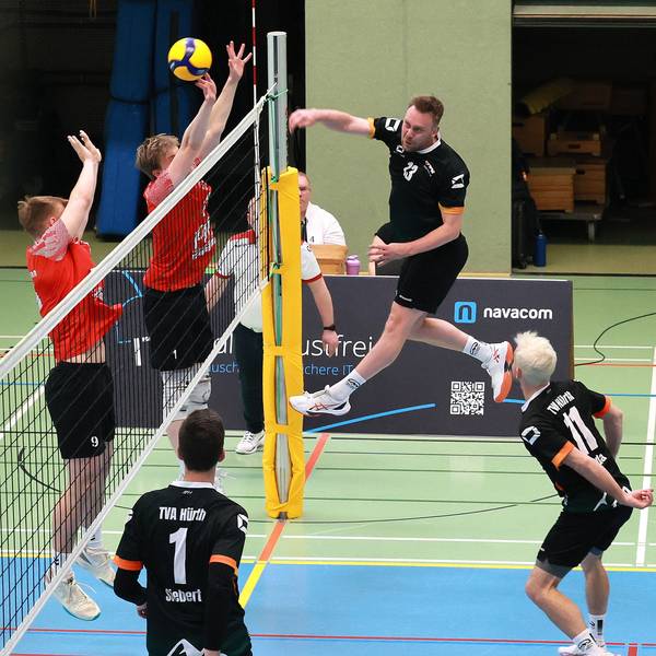 Das Foto zeigt einen Hürther Volleyballer im schwarzen Trikot, der den Ball über das Netz schmettert.