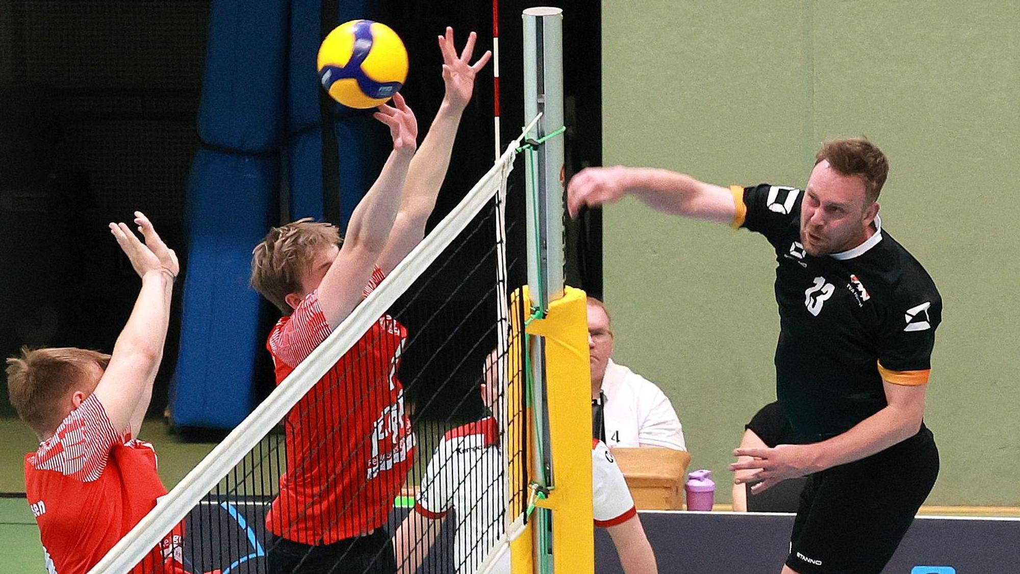 Das Foto zeigt einen Hürther Volleyballer im schwarzen Trikot, der den Ball über das Netz schmettert.