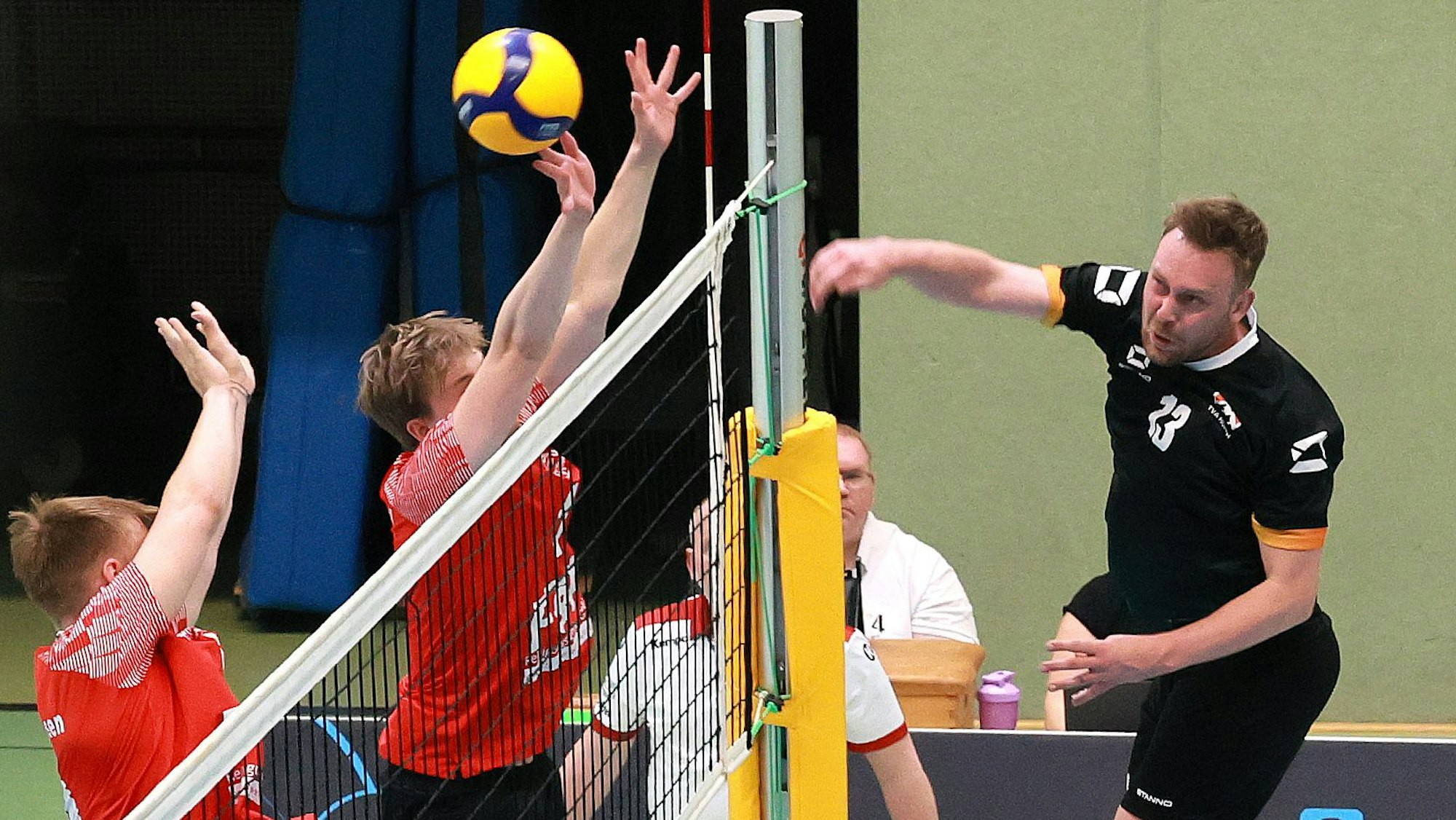 Das Foto zeigt einen Hürther Volleyballer im schwarzen Trikot, der den Ball über das Netz schmettert.