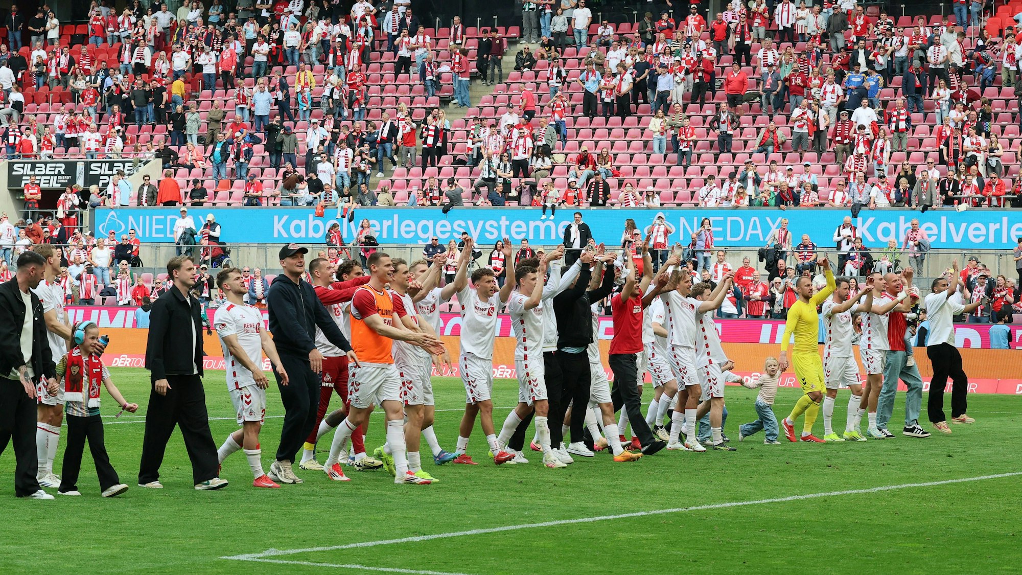 Mit Kind und Kegel und den verletzten Spielern: Die Mannschaft des 1. FC Köln feiert nach dem Spiel vor der Südtribüne.