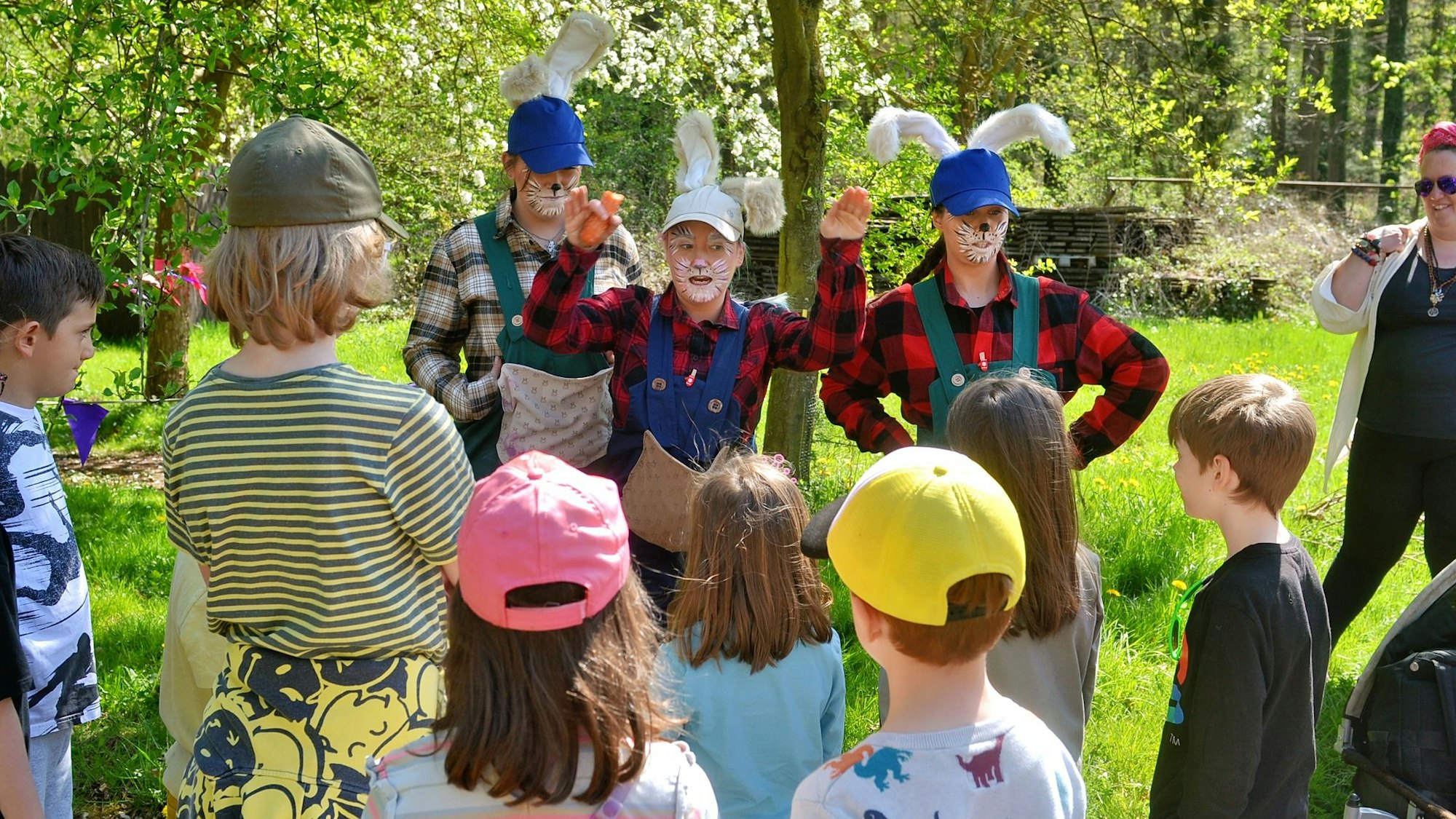 Drei als Osterhasen verkleidete Darsteller erklären den Kindern, wo sie suchen dürfen.