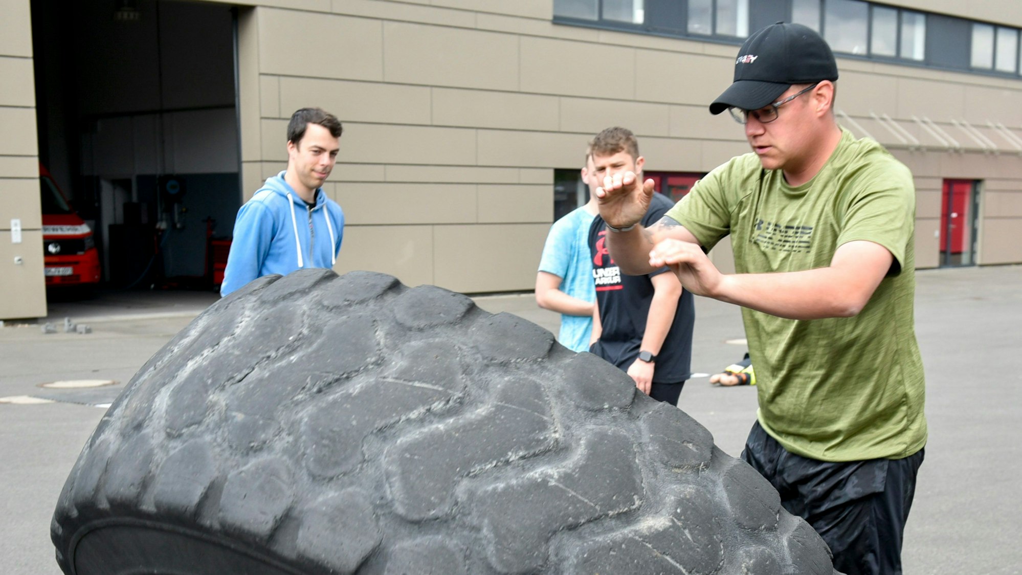 Das Foto zeigt einen Sportler, der einen Reifen hebt und kippt.