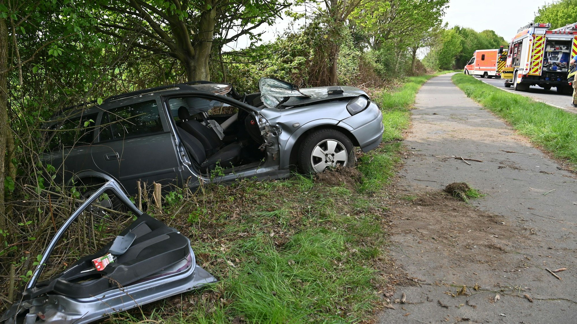 Das Bild zeigt ein Auto, das gegen einen Baum am Straßenrand geprallt ist.