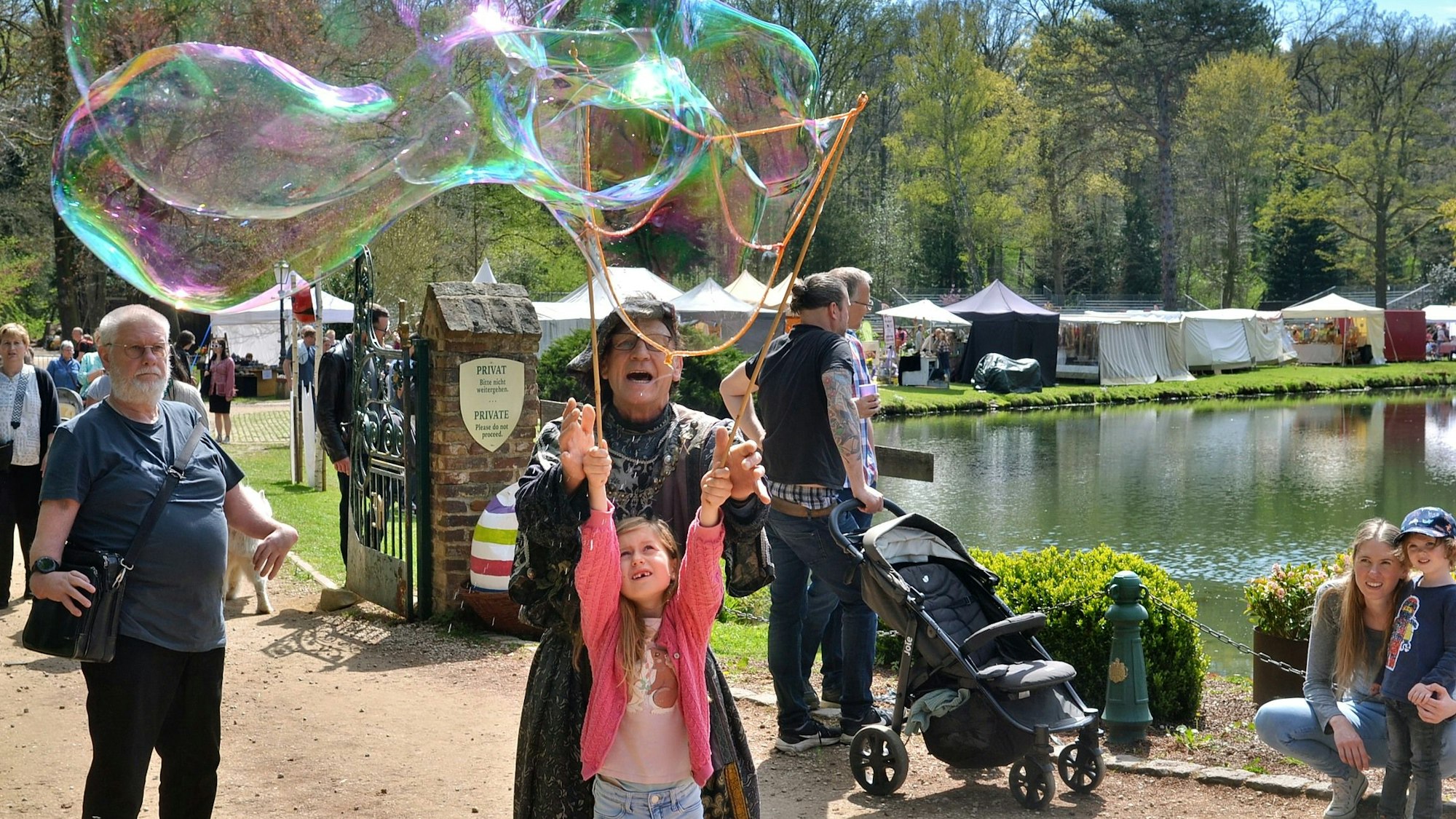 Ein Artist zaubert mit einem Mädchen riesige Seifenblasen.