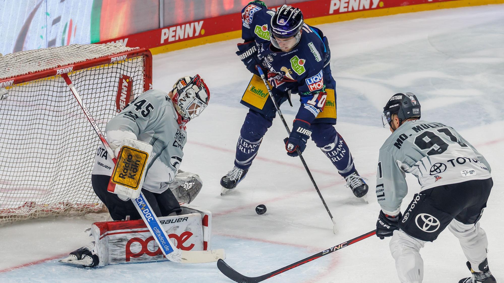 Haie-Backup Tobias Ancicka (l) und Kapitän Moritz Müller verteidigen das Tor gegen Berlins Lean Bergmann (M).