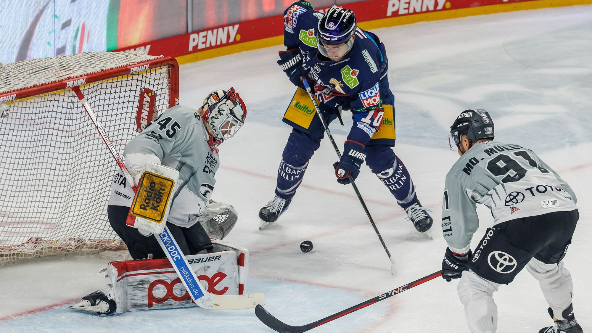 Haie-Backup Tobias Ancicka (l) und Kapitän Moritz Müller verteidigen das Tor gegen Berlins Lean Bergmann (M).