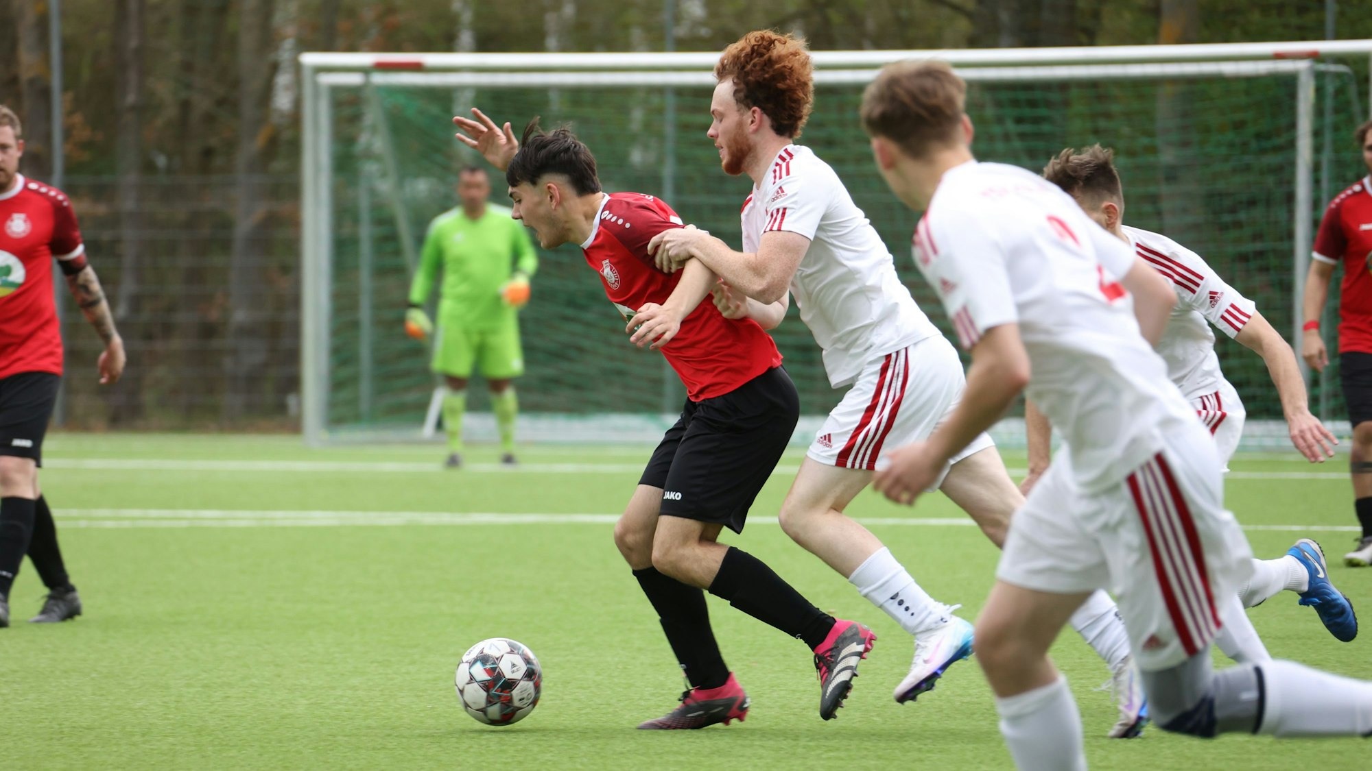 Ein Fußballer zieht einen Gegenspieler am Arm.