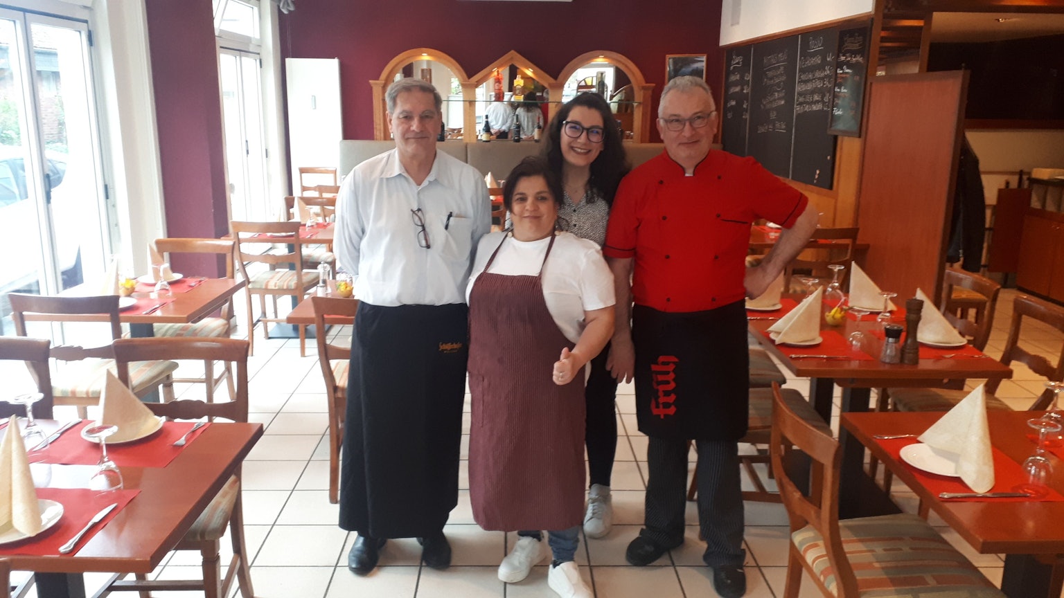 Zwei Männer und eine Frau stehen im Gastraum eines Restaurants.