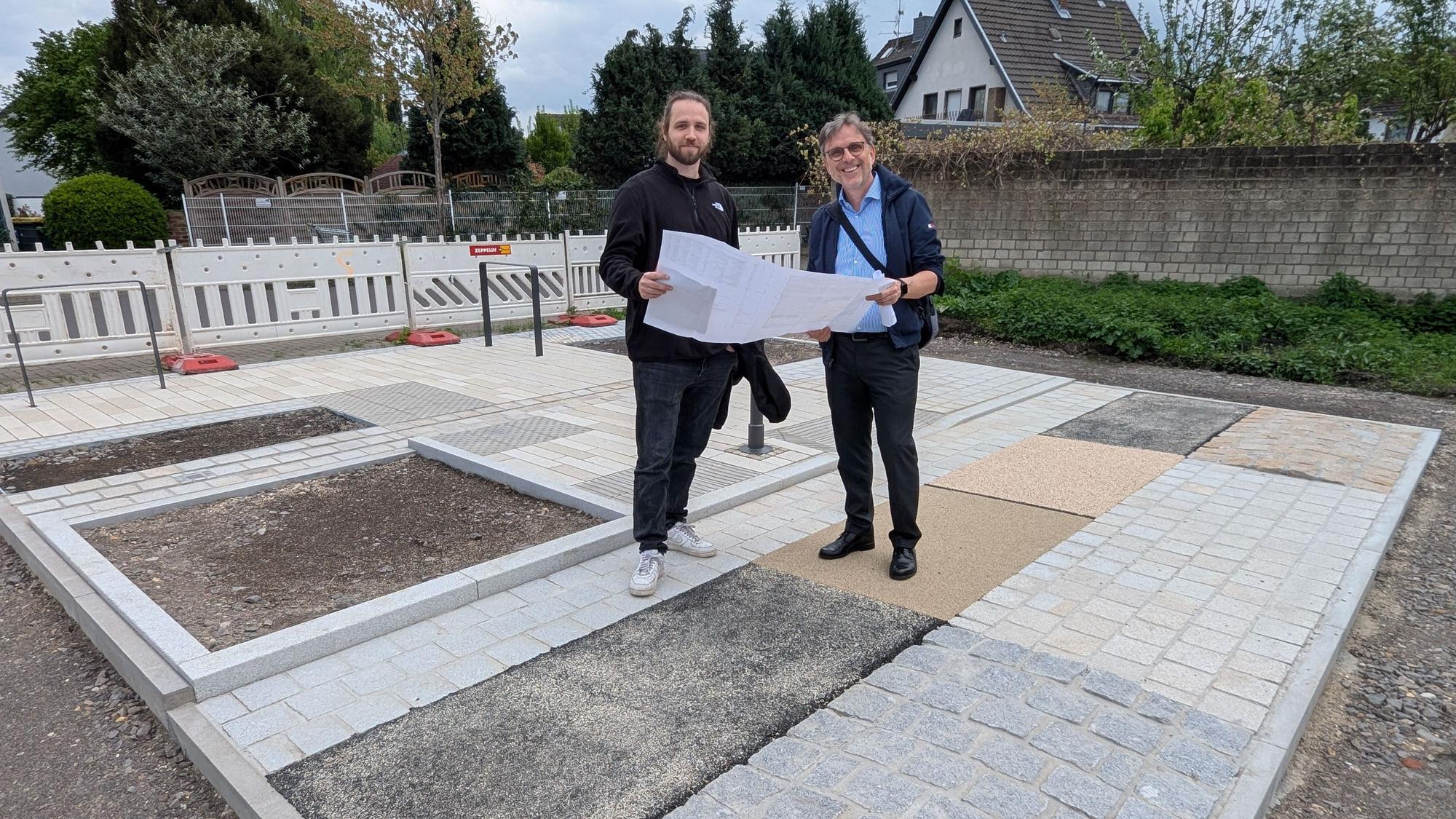 Das Foto zeigt die beiden Projektverantwortlichen mit einem großen Faltplan auf der Musterfläche.