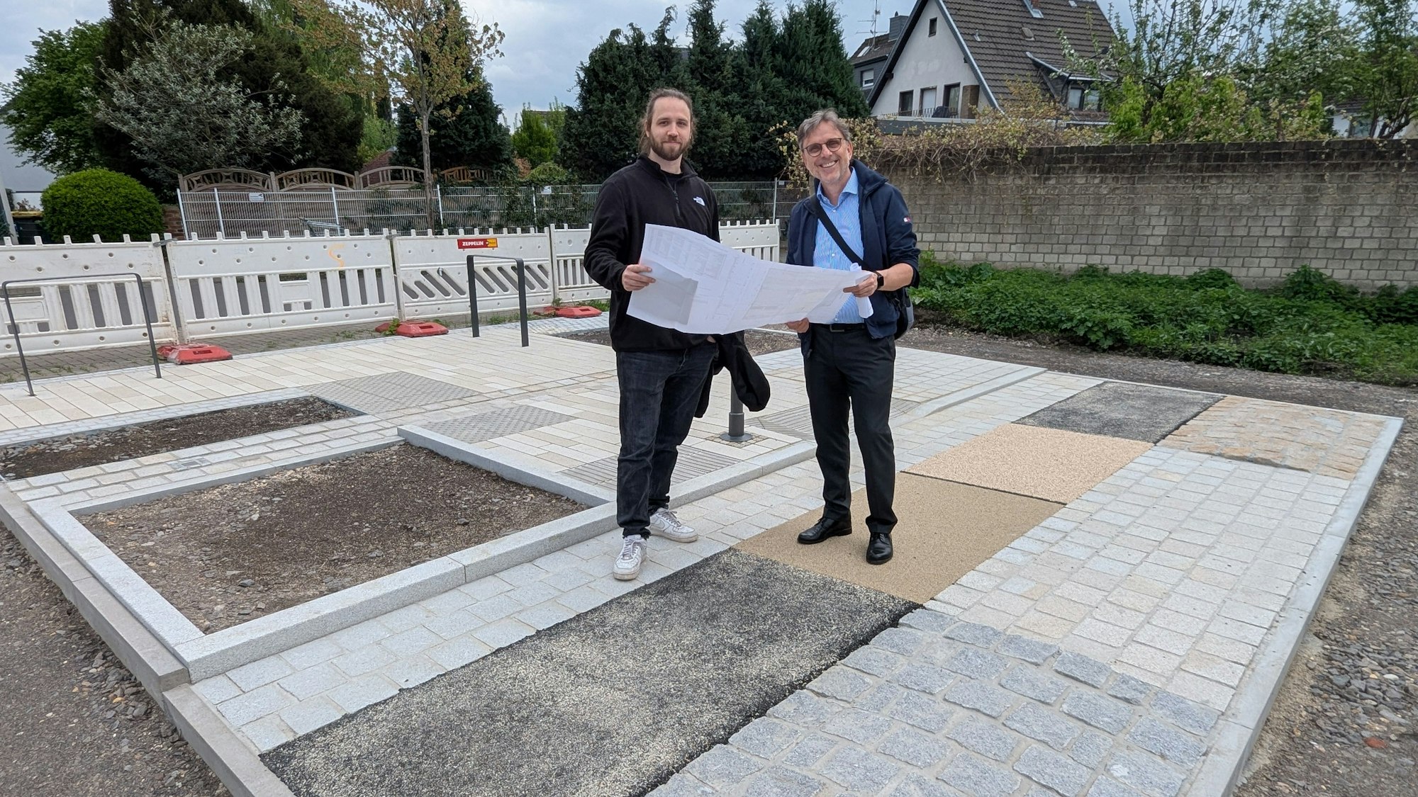 Das Foto zeigt die beiden Projektverantwortlichen mit einem großen Faltplan auf der Musterfläche.