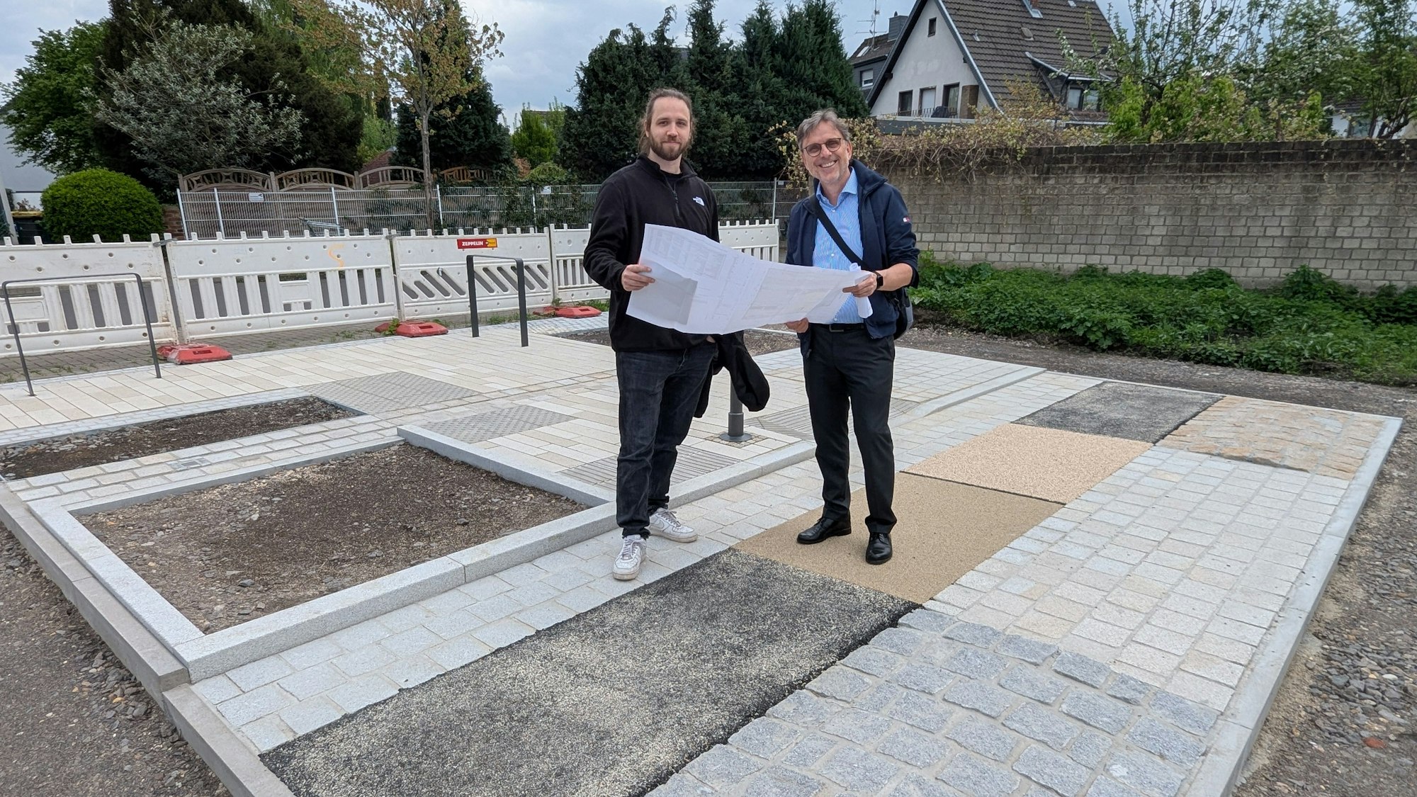 Das Foto zeigt die beiden Projektverantwortlichen mit einem großen Faltplan auf der Musterfläche.