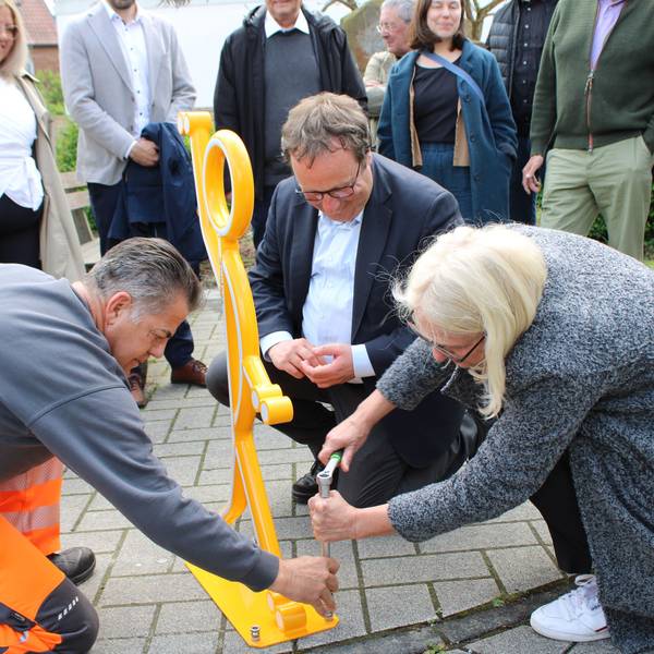 Verkehrsminister Oliver Krischer und Bürgermeisterin Claudia Wieja bringen einen Aufsteller für mehr Sicherheit am Knoten Bachstraße/ Rathausstraße/ Am Bungert an.