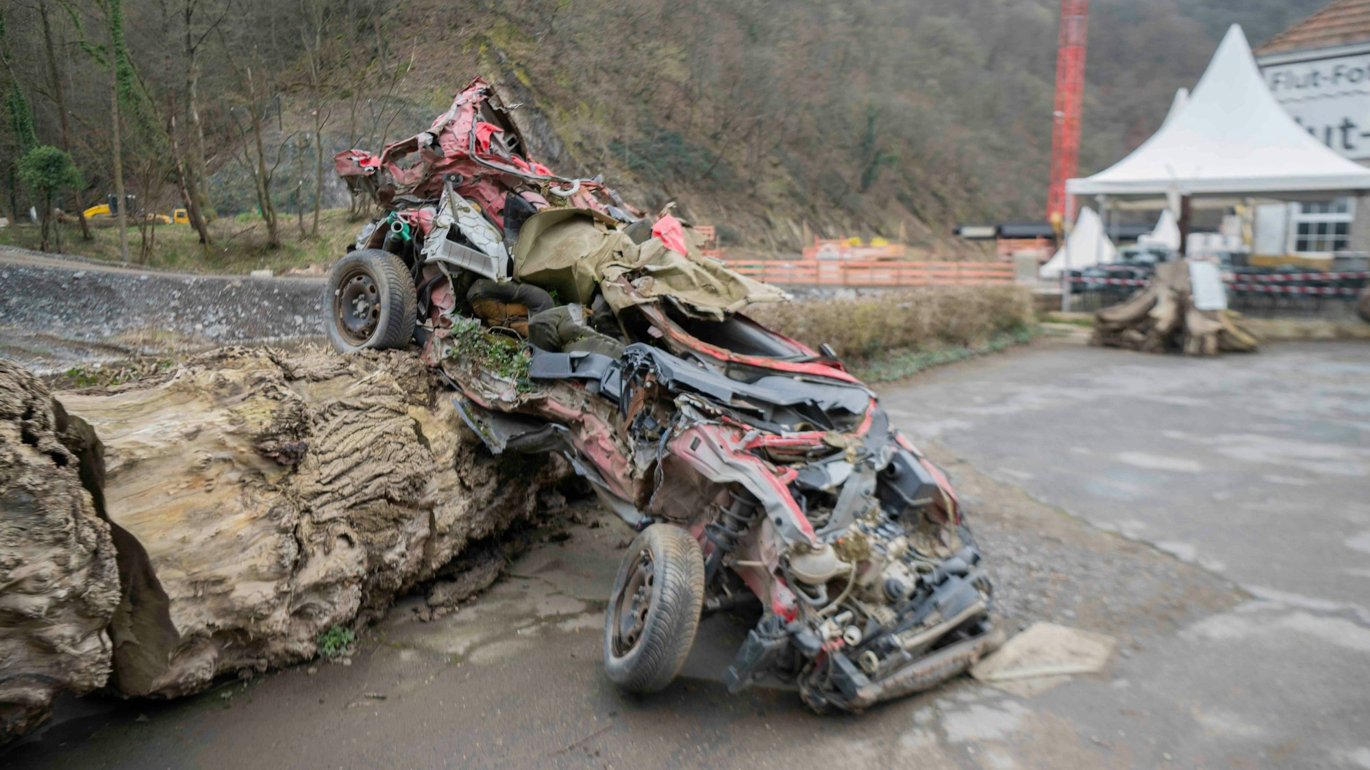Ein bei der Flut zerstörtes Schrottauto wurde auf einem Holzstamm drapiert.