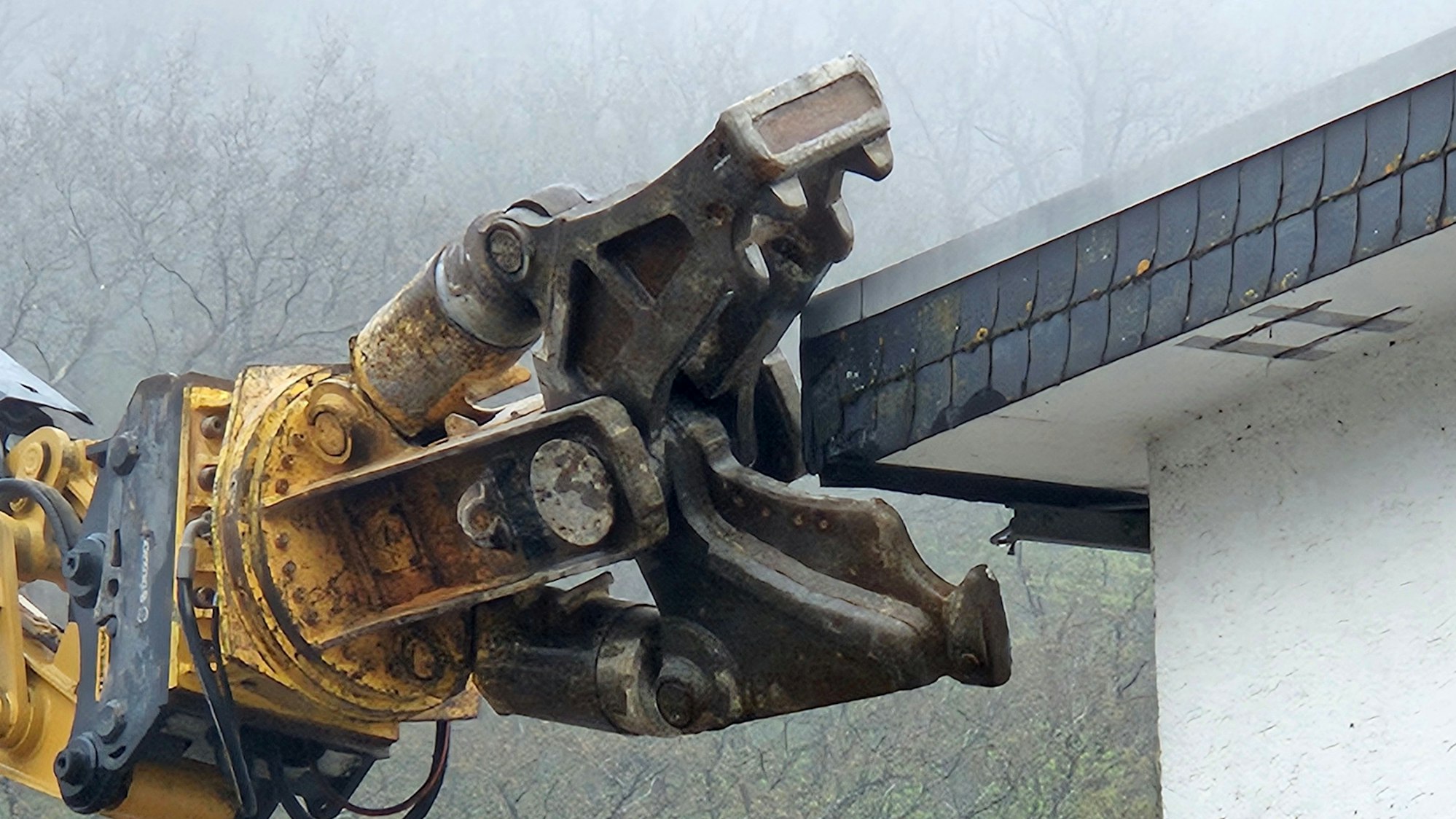 Das Bild zeigt einen Hydraulikgreifer, der an der Stahlbetondecke arbeitet.