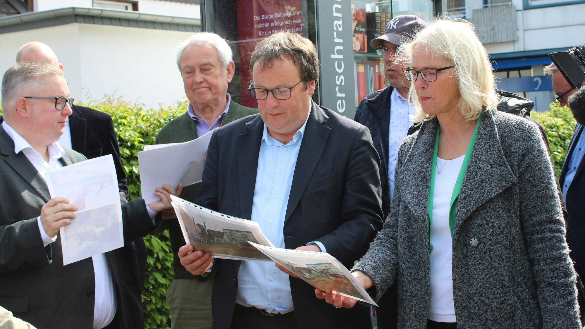 Oliver Krischer und Claudia Wieja sehen Vorher-Nachher-Fotos des jetzt klimafreundlicher gestalteten Frouardplatzes.