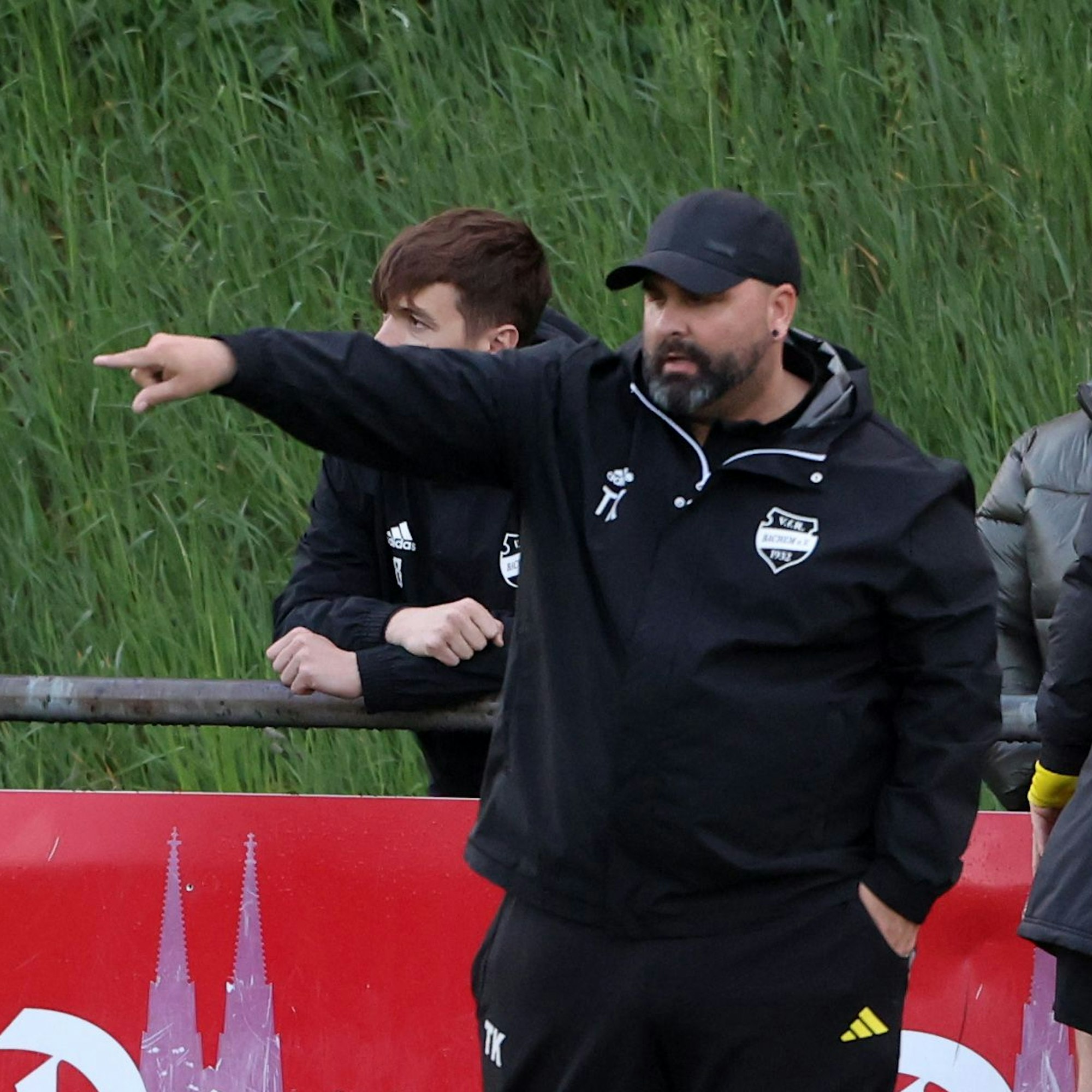 Das Foto zeigt einen Trainer mit ausgestreckten Arm und Zeigefinger