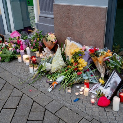 20.04.2025, Niedersachsen, Oldenburg: Zahlreiche Blumen und Kerzen stehen in der Innenstadt an einer Hauswand in der Achternstraße, in der am frühen Sonntagmorgen ein Mensch von Schüssen aus einer Polizeiwaffe tödlich verletzt wurde. Nach einer Auseinandersetzung in einem Lokal in der Innenstadt war der mutmaßliche Angreifer von Schüssen aus einer Polizeiwaffe tödlich verletzt worden. Foto: Hauke-Christian Dittrich/dpa - ACHTUNG: Foto des Toten gepixelt +++ dpa-Bildfunk +++