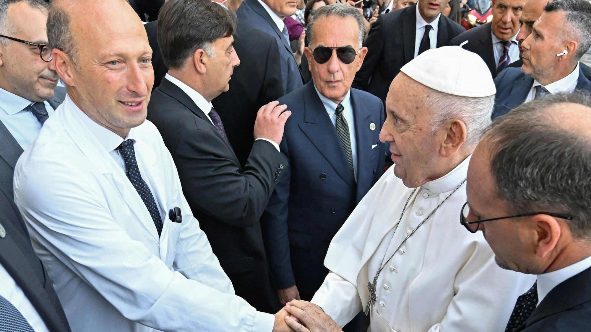 Sergio Alfieri (l.) schüttelt Papst Franziskus die Hand nach einem Krankenhausaufenthalt des Pontifex im Jahr 2023.