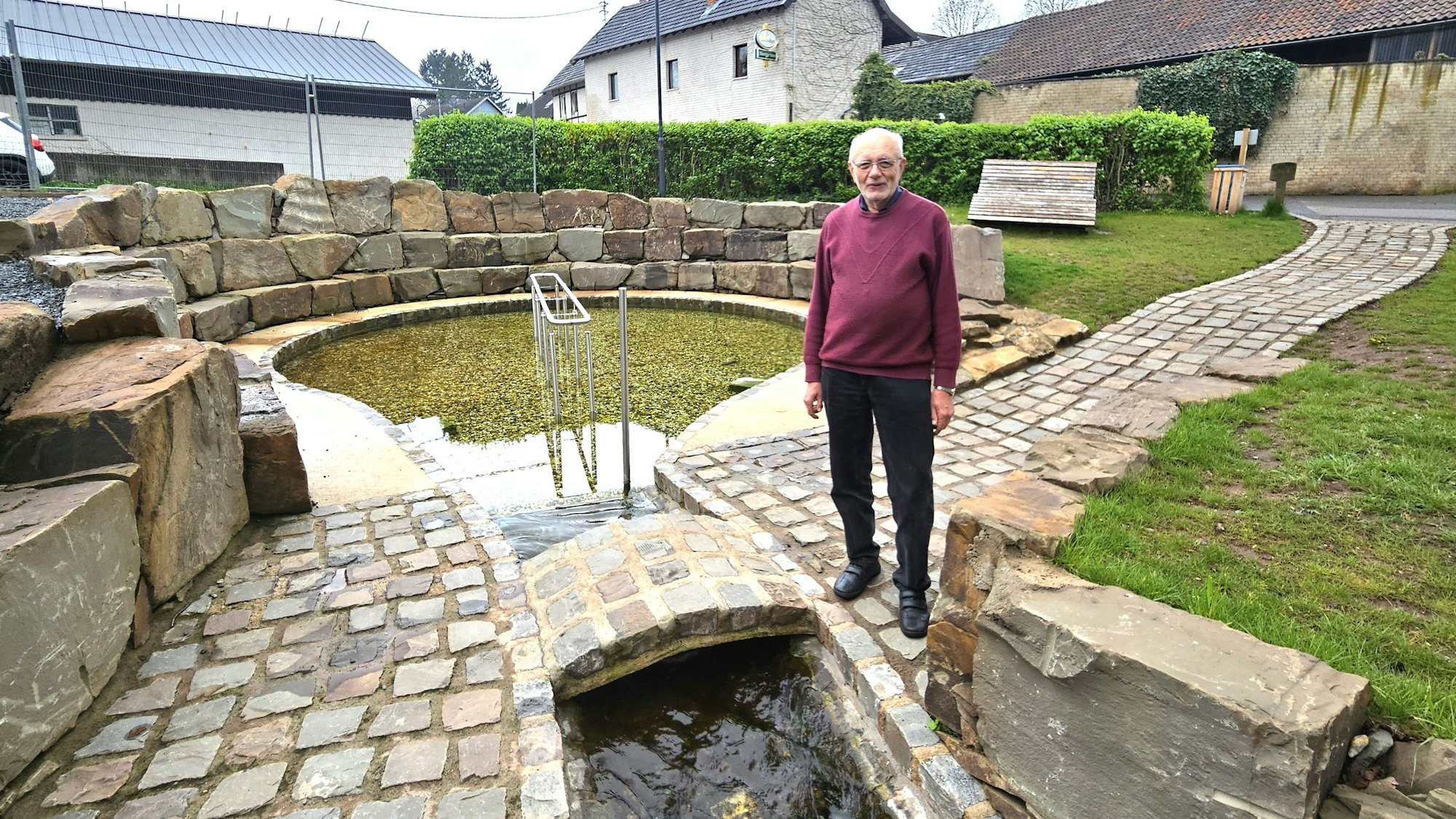 Ortsvorsteher Hans Reiff steht vor der neu gestalteten Klausenquelle.