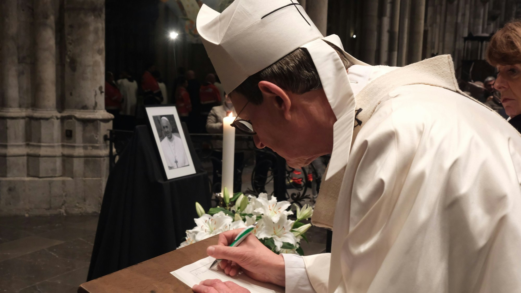 Kardinal Rainer Woelki trägt sich im Kölner Dom ins Kondolenzbuch für Papst Franziskus ein.