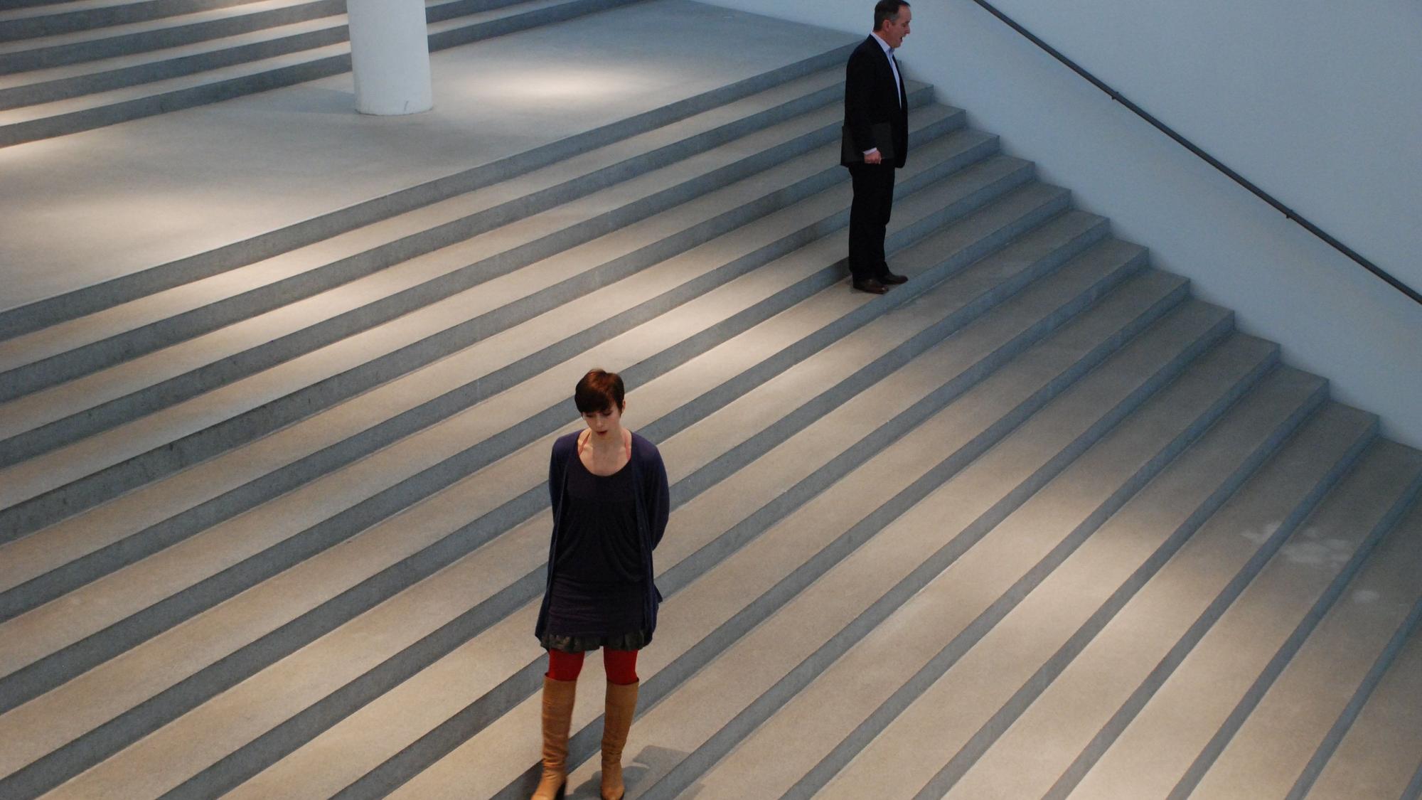 Eine Frau und ein Mann stehen auf einer großen Treppe.