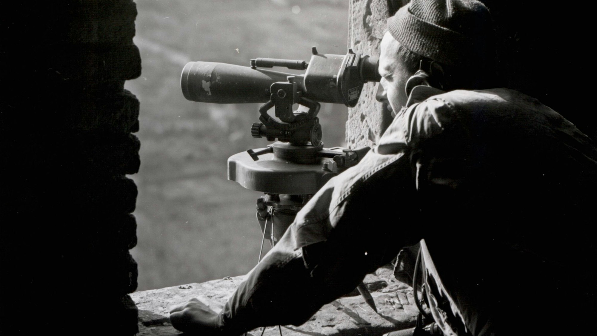 Zu sehen ist auf einem alten Schwarz-Weiß-Foto ein US-Soldat, der mit einem Fernrohr von einem Kirchturm schaut.