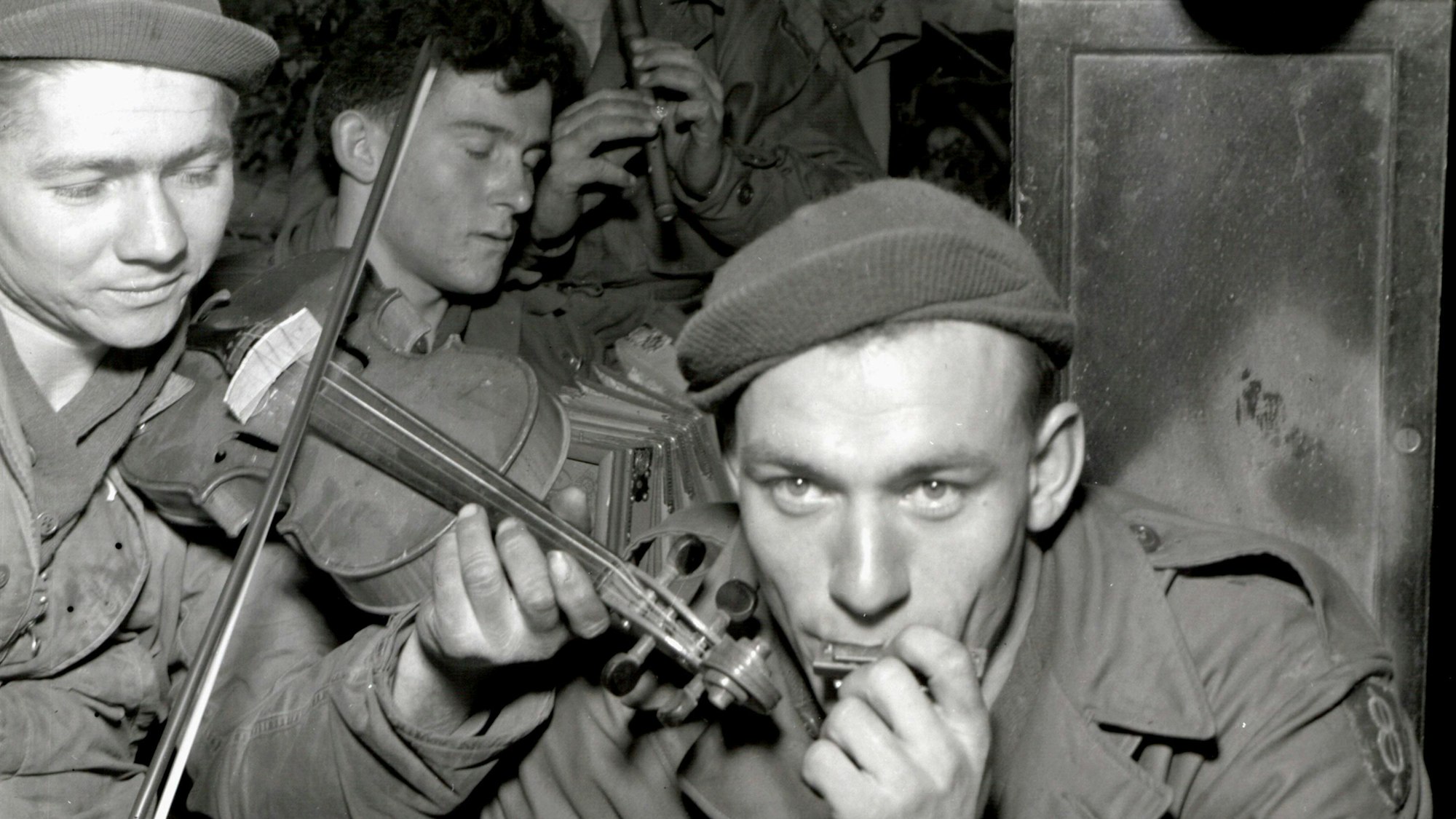 Zu sehen sind auf einem alten Schwarz-Weiß-Foto US-Soldaten, die musizieren.
