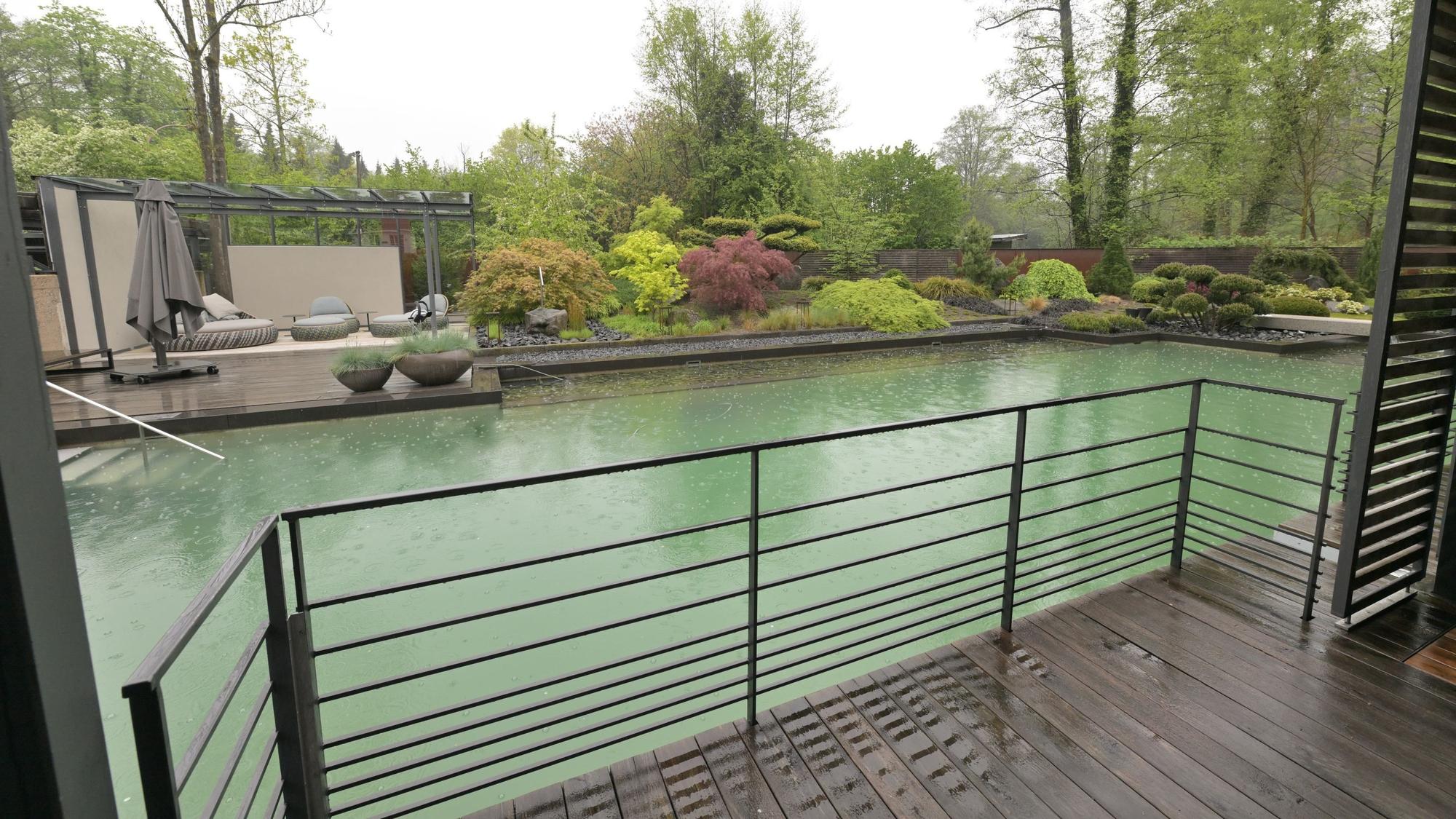 Hinter einem Balkon liegt ein Pool.