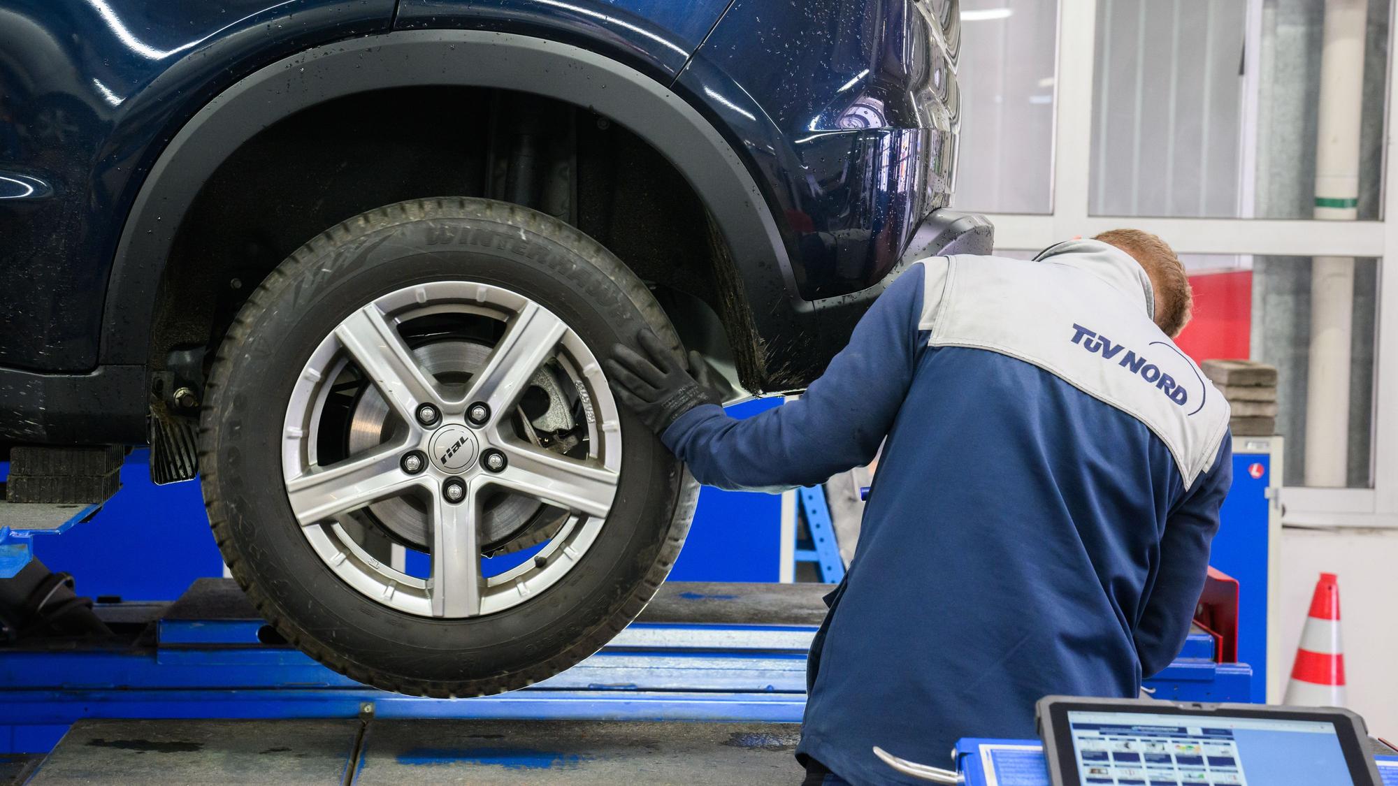 Ein TÜV-Prüfer begutachtet ein Auto bei der Hauptuntersuchung.