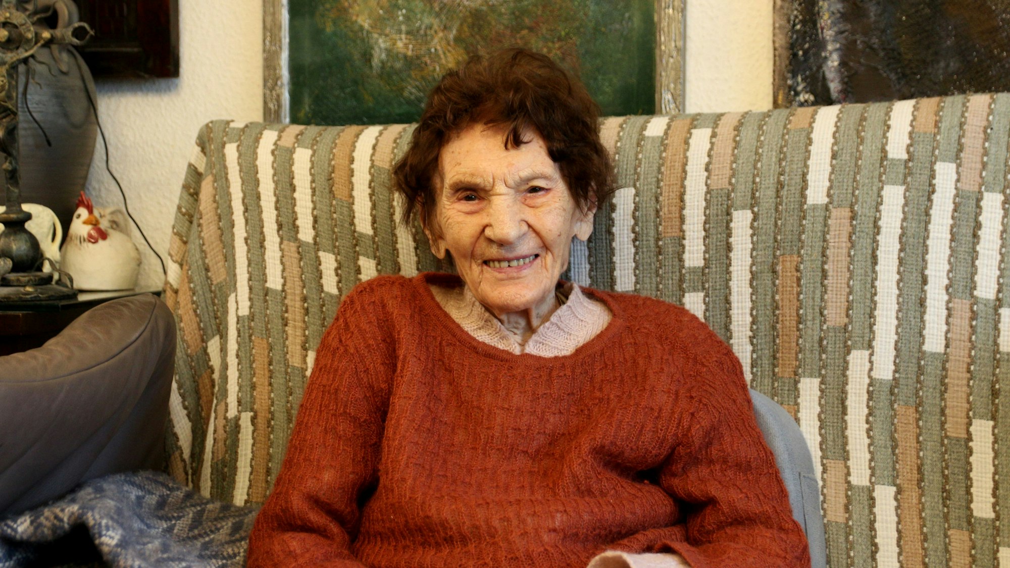 Eine 101-jährige Frau sitzt auf einem Sofa.