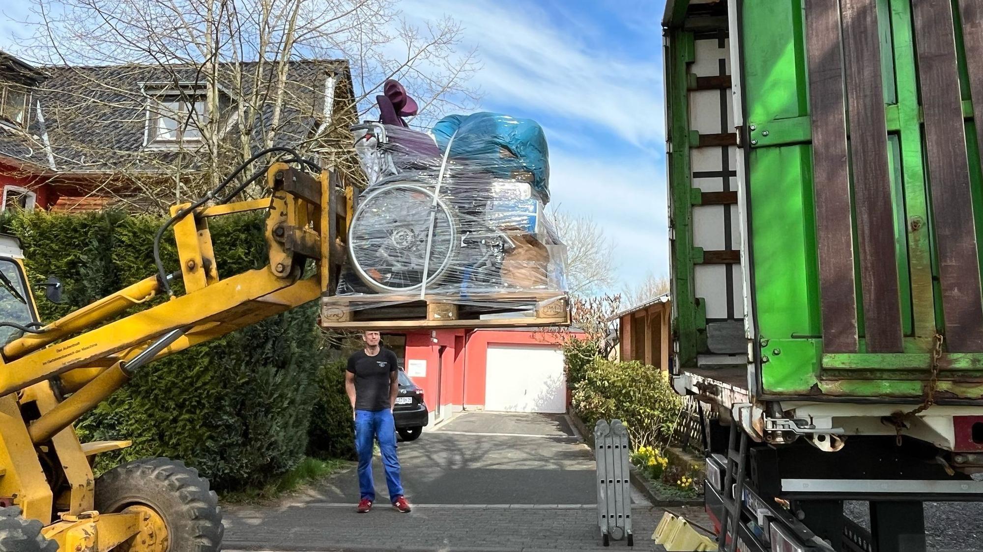 Ein Bagger verlädt Hilfsgüter in einen LKW.