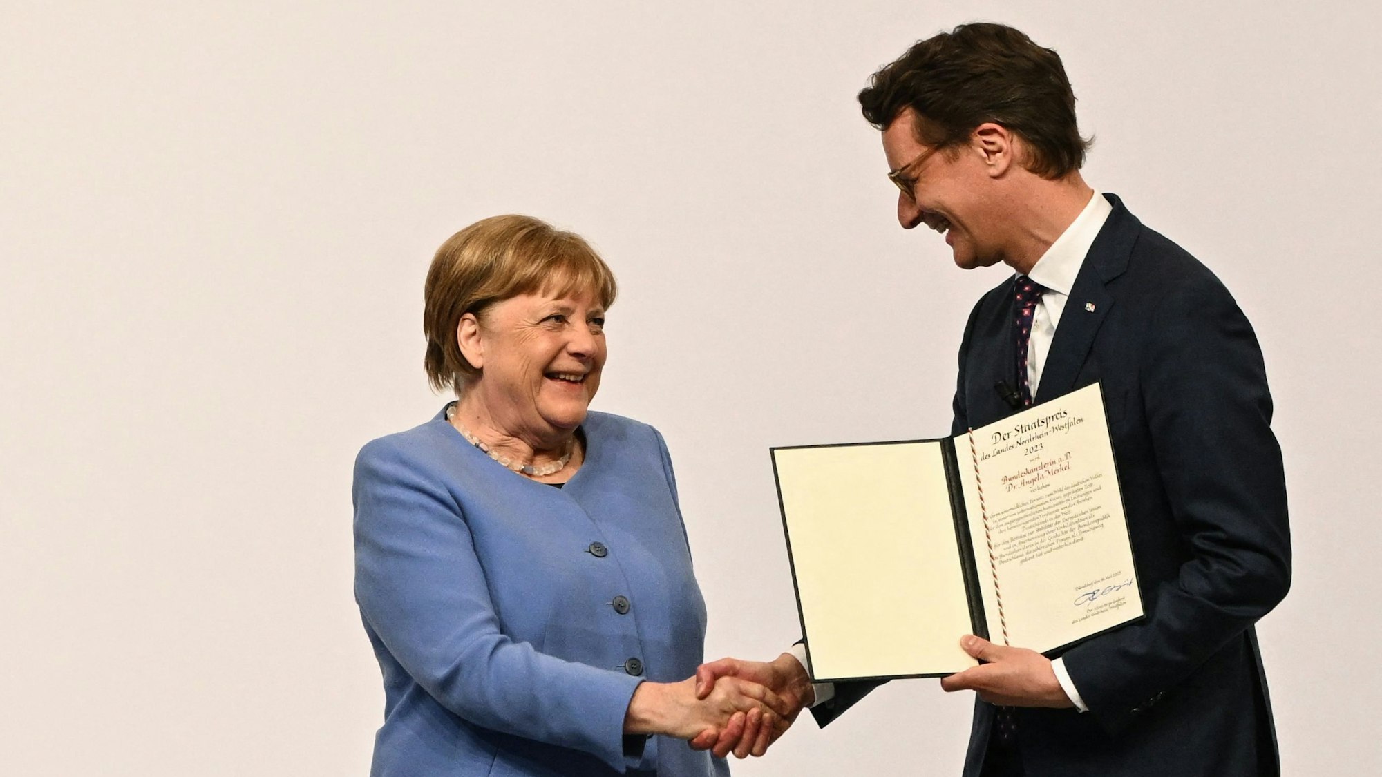 Ministerpräsident Wüst unterhält gute Verbindungen zu Ex-Kanzlerin Merkel. Hier überreicht er ihr den Staatspreis des Landes NRW. (Archiv)