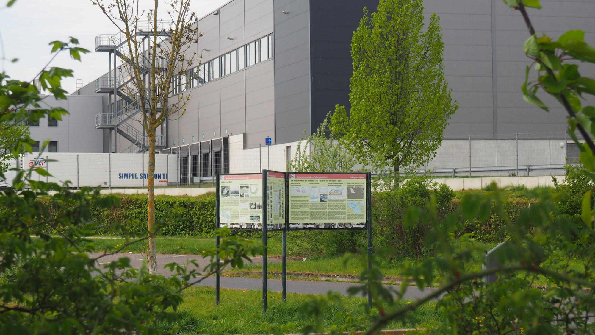 Zu sehen ist ein Gebäude im Hintergrund, davor mehrere Informationstafeln.