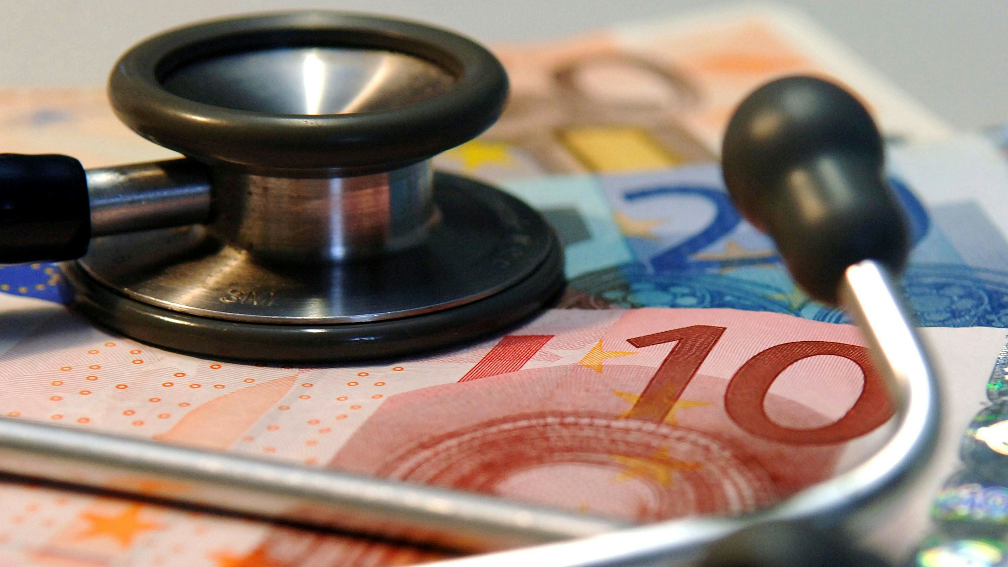 Ein Stethoskop liegt auf mehreren Geldscheinen,