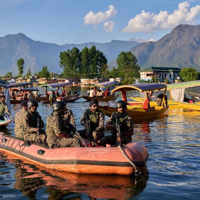 Paramilitärische Soldaten patrouillieren auf einem Schlauchboot, während indische Touristen eine Bootsfahrt unternehmen.