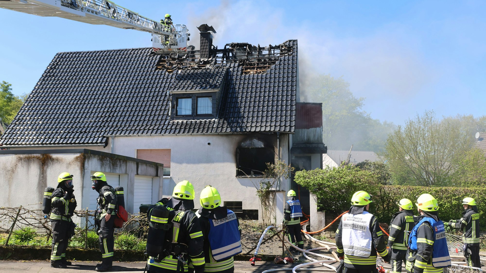 Mehrere Feuerwehrleute löschen, auch per Drehleiter, einen Wohnhausbrand.