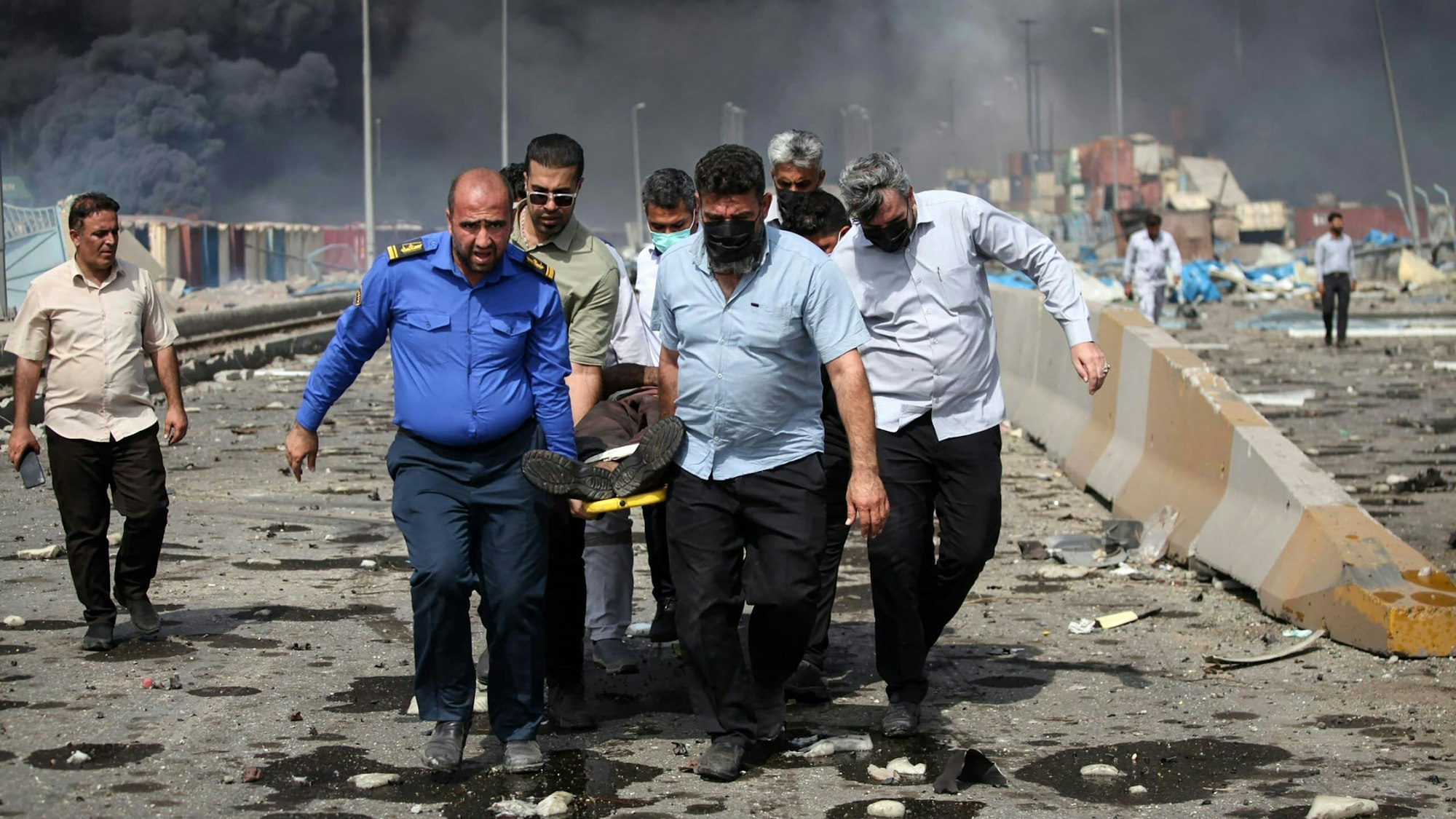 Menschen transportieren einen verletzten Mann nach einer Explosion am Hafendock von Shahid Rajaee.