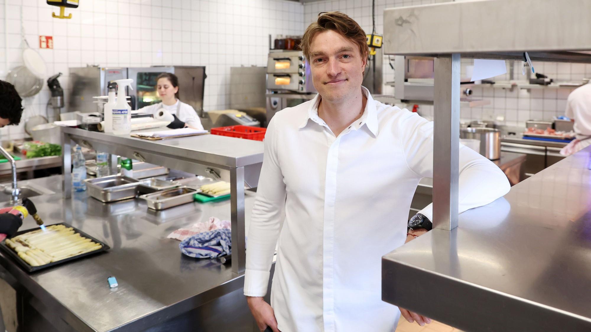 Ein Mann - er ist Küchenchef - steht in der Küche eines Restaurants.