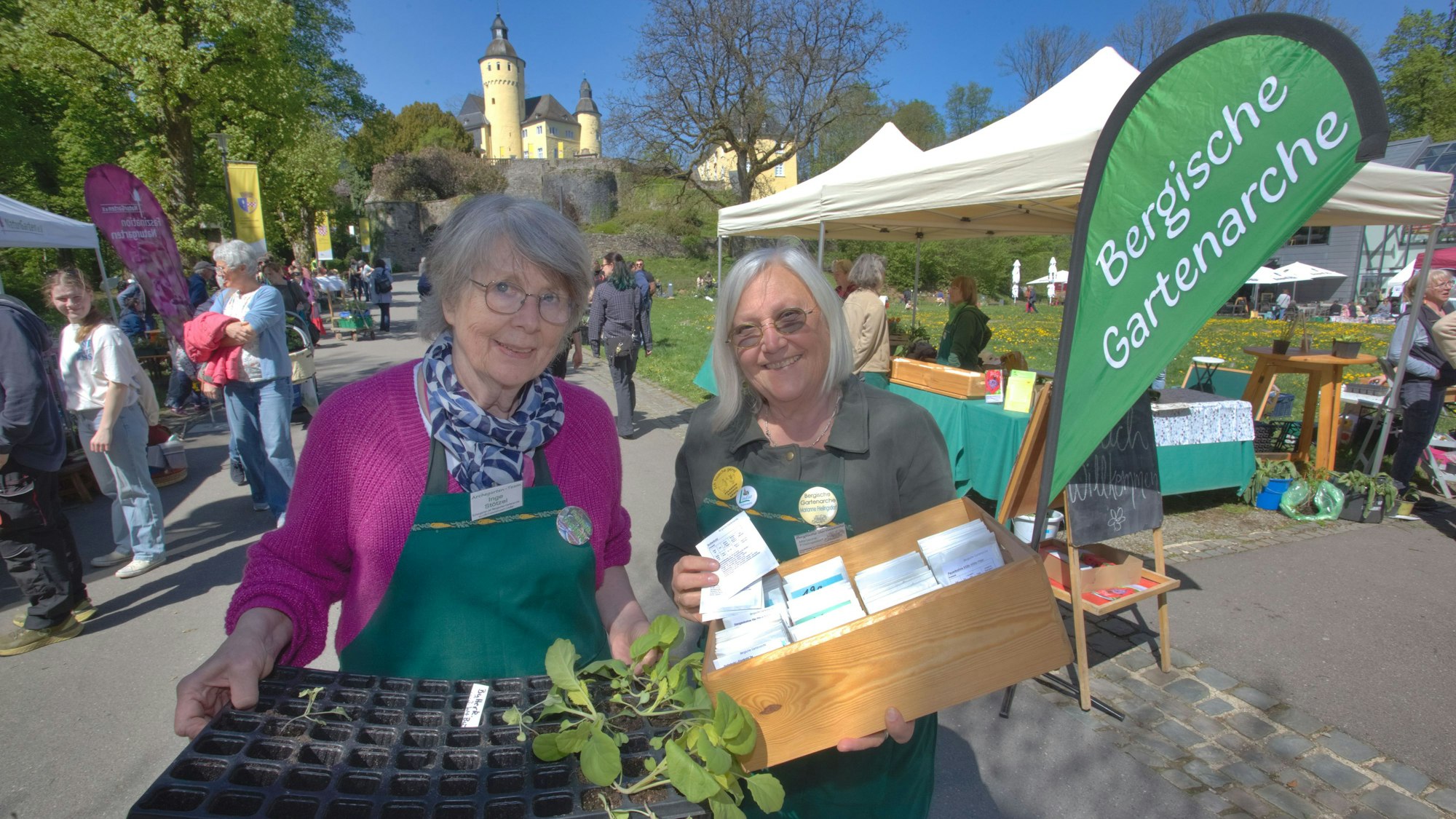 Zwei Damen mit Tabletts in der Hand, Im Hintergrund das Schloss.