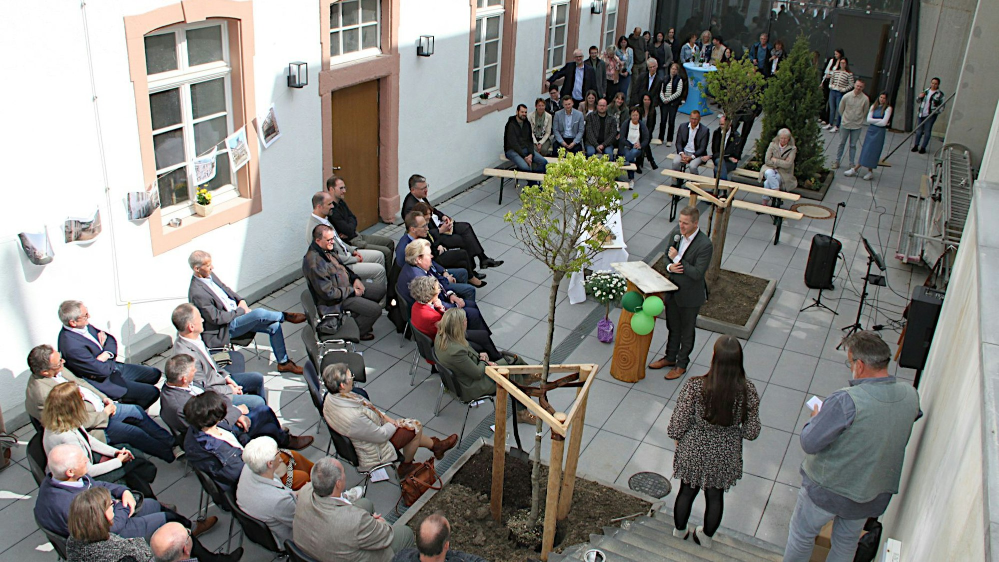 Mehrere Besucher haben im Innenhof Platz genommen, Landrat Markus Ramers steht am Rednerpult.