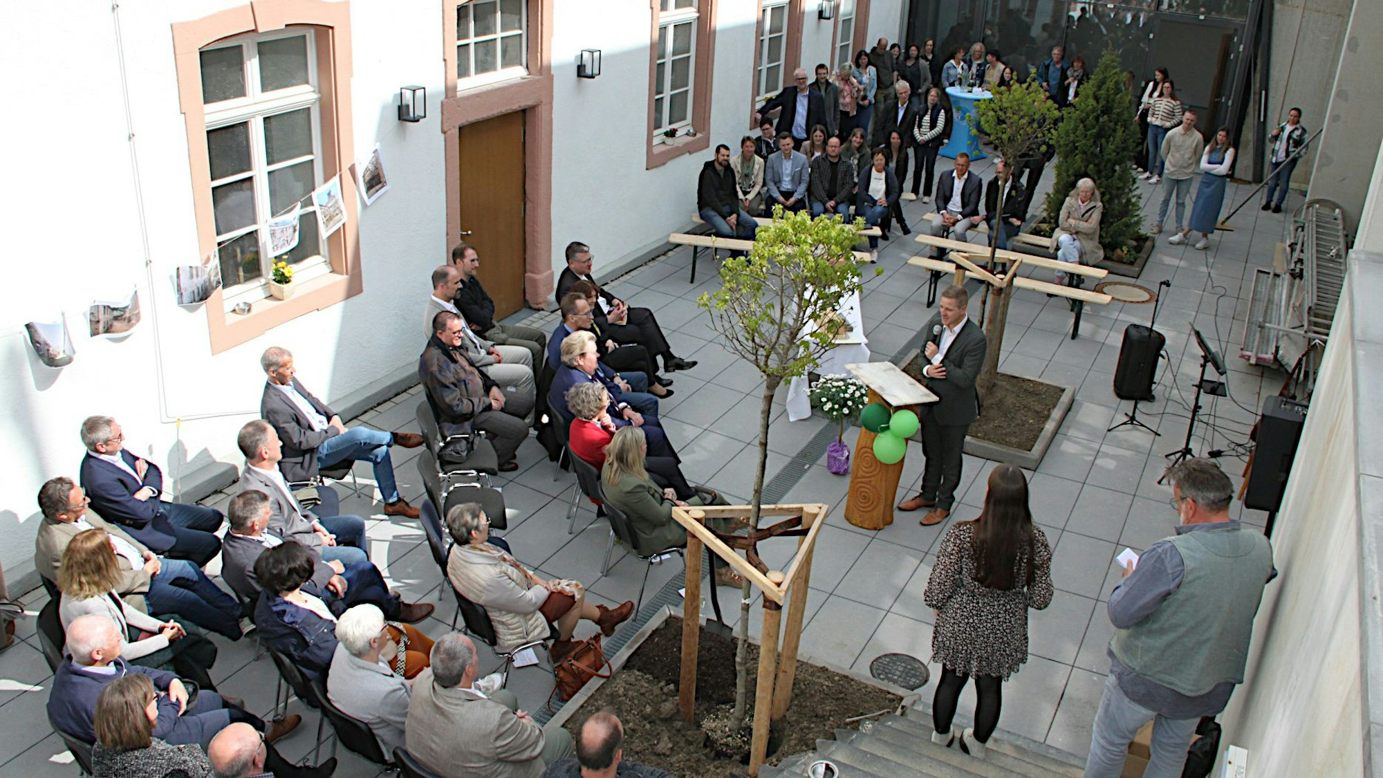 Mehrere Besucher haben im Innenhof Platz genommen, Landrat Markus Ramers steht am Rednerpult.