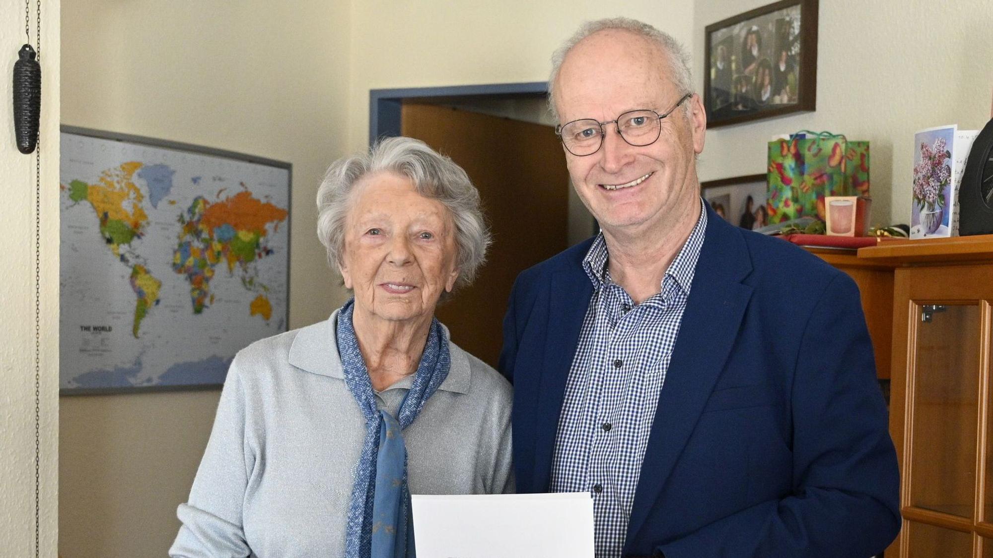 Das Bild zeigt Edith Stief und Hans-Peter Schick, die nebeneinander stehen. Er hält eine Urkunde in der Hand.