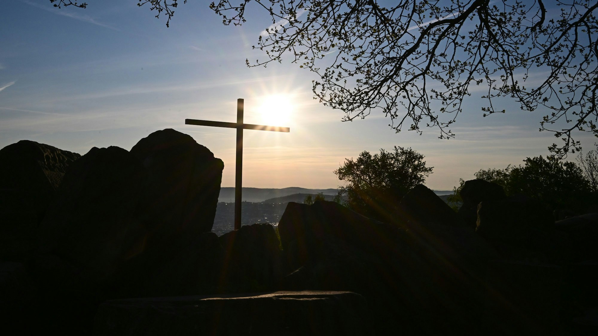 Die Sonne geht vor einem Kreuz am Birkenkopf auf. Der Birkenkopf ist ein künstlicher Hügel, aufgeschüttet aus Ruinen aus dem 2. Weltkrieg.