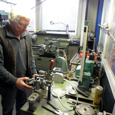 Hans Küppers steht an einer Werkbank, auf der zahlreiche Werkzeuge liegen.