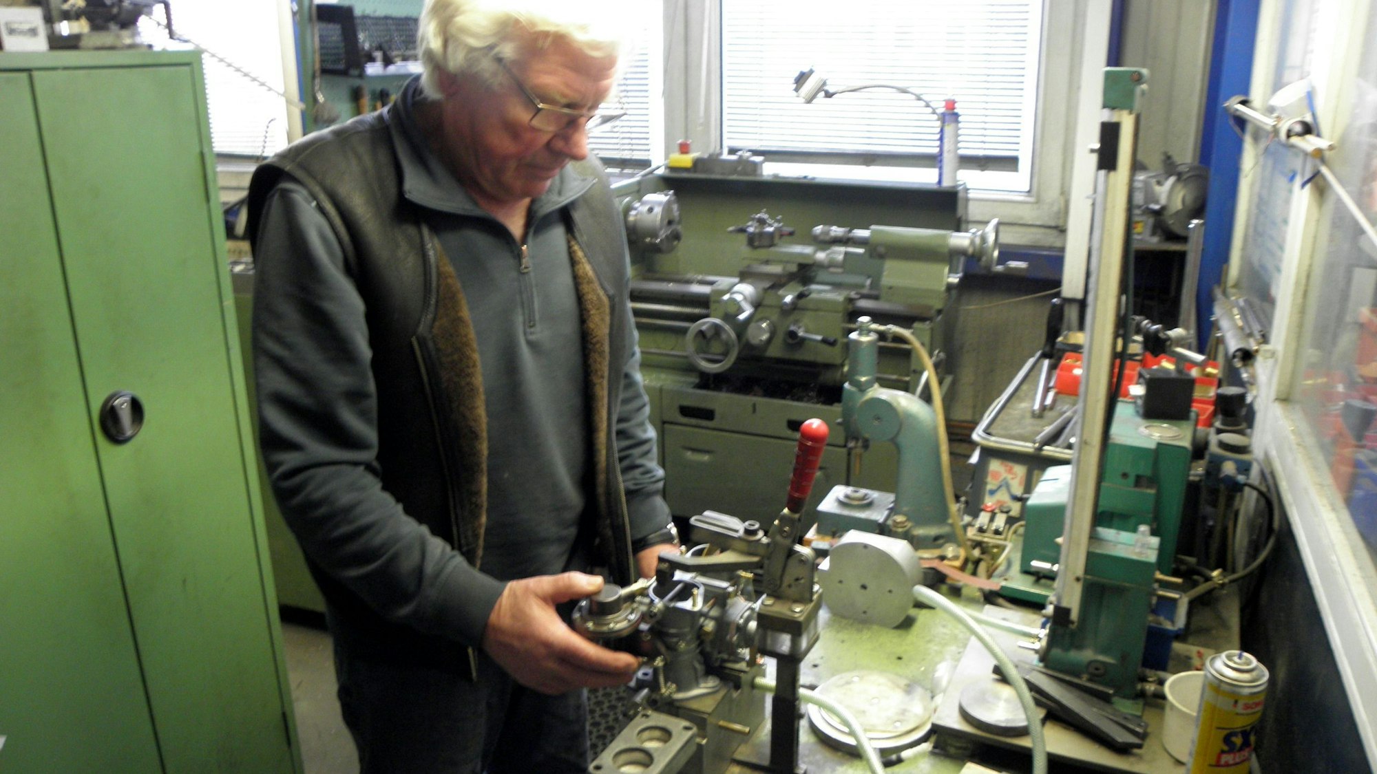 Hans Küppers steht an einer Werkbank, auf der zahlreiche Werkzeuge liegen.